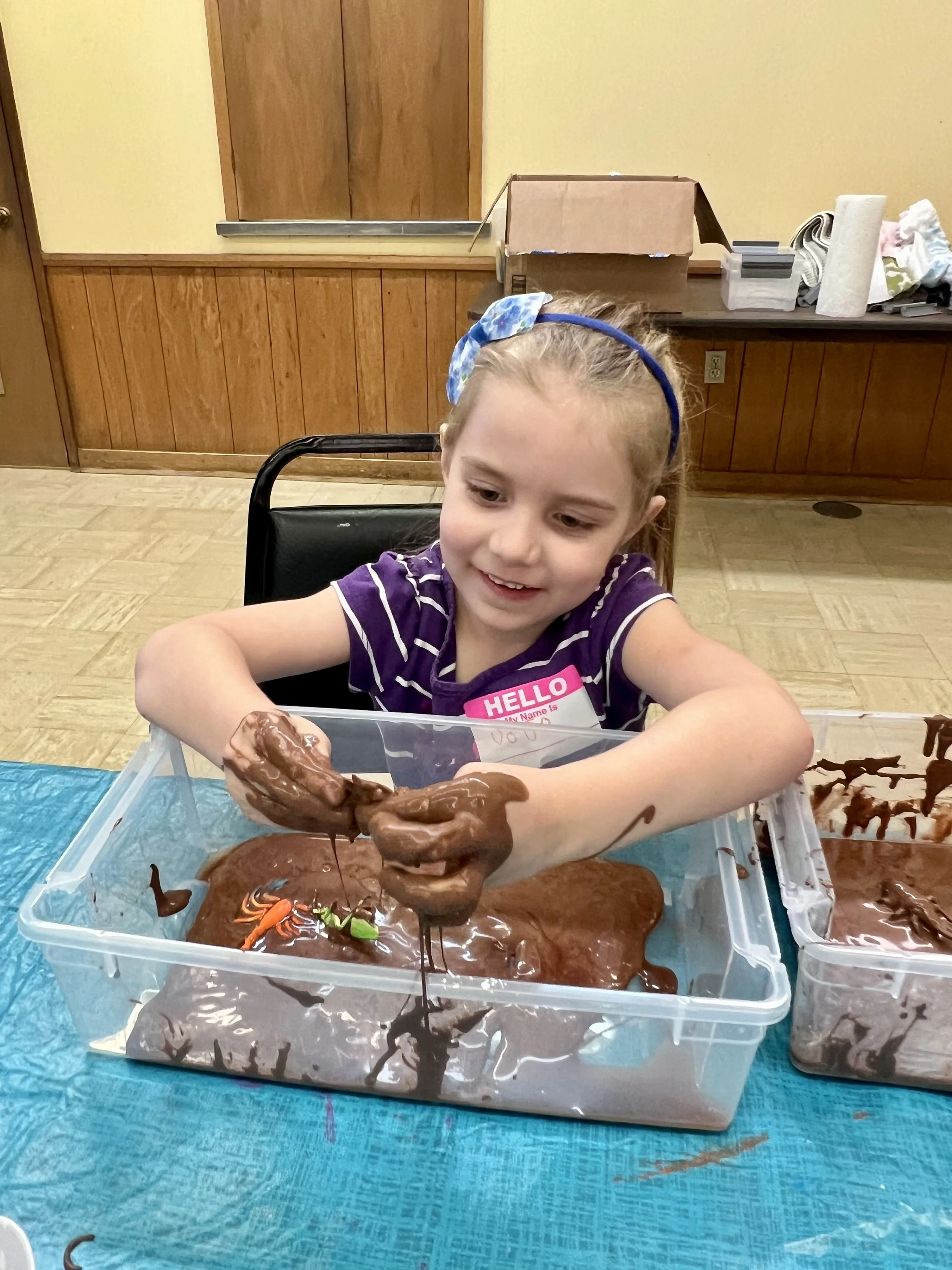 girl playing with toys in a tub of chocolate pudding 