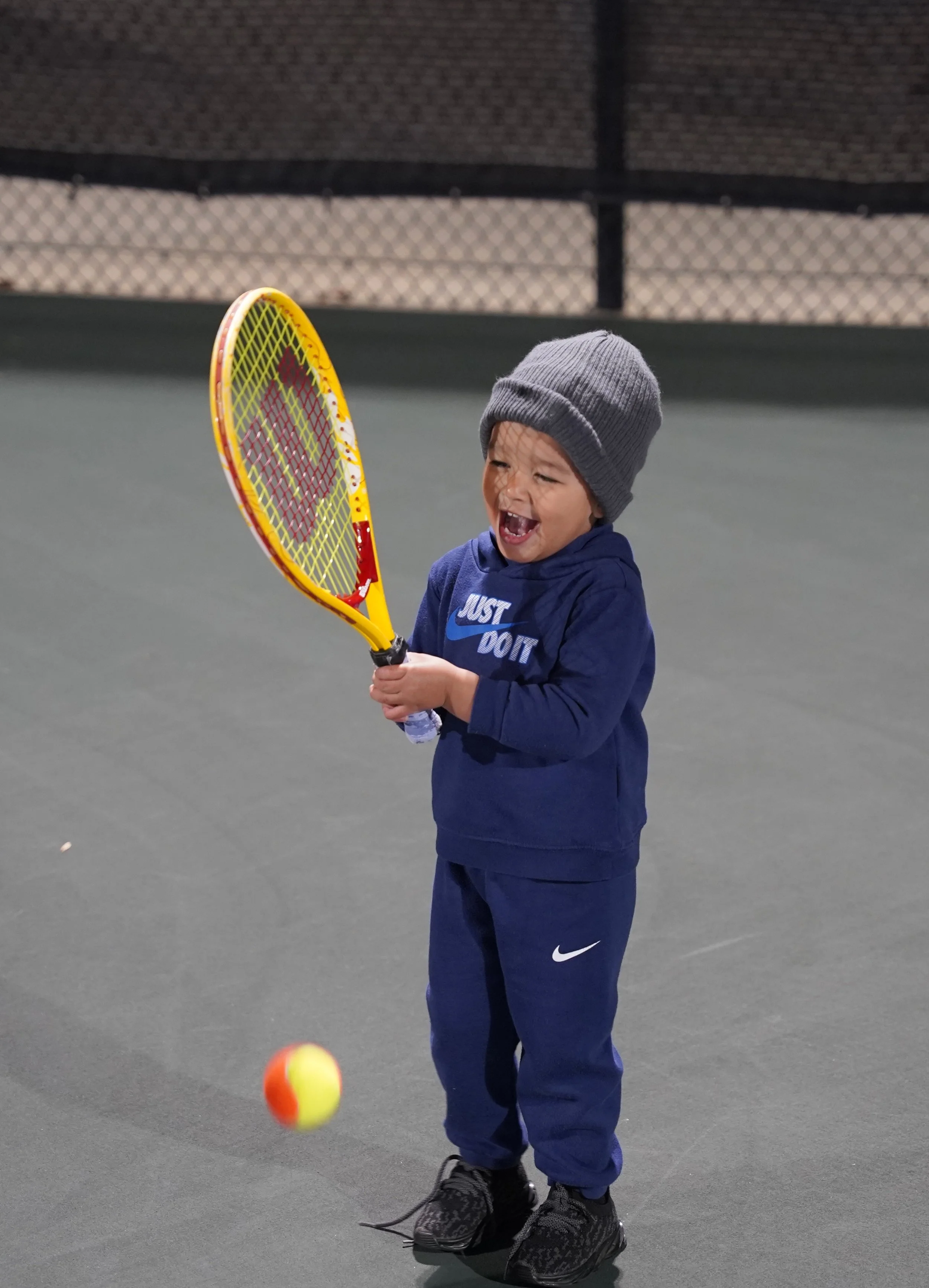 boy holding tennis racket with tennis ball
