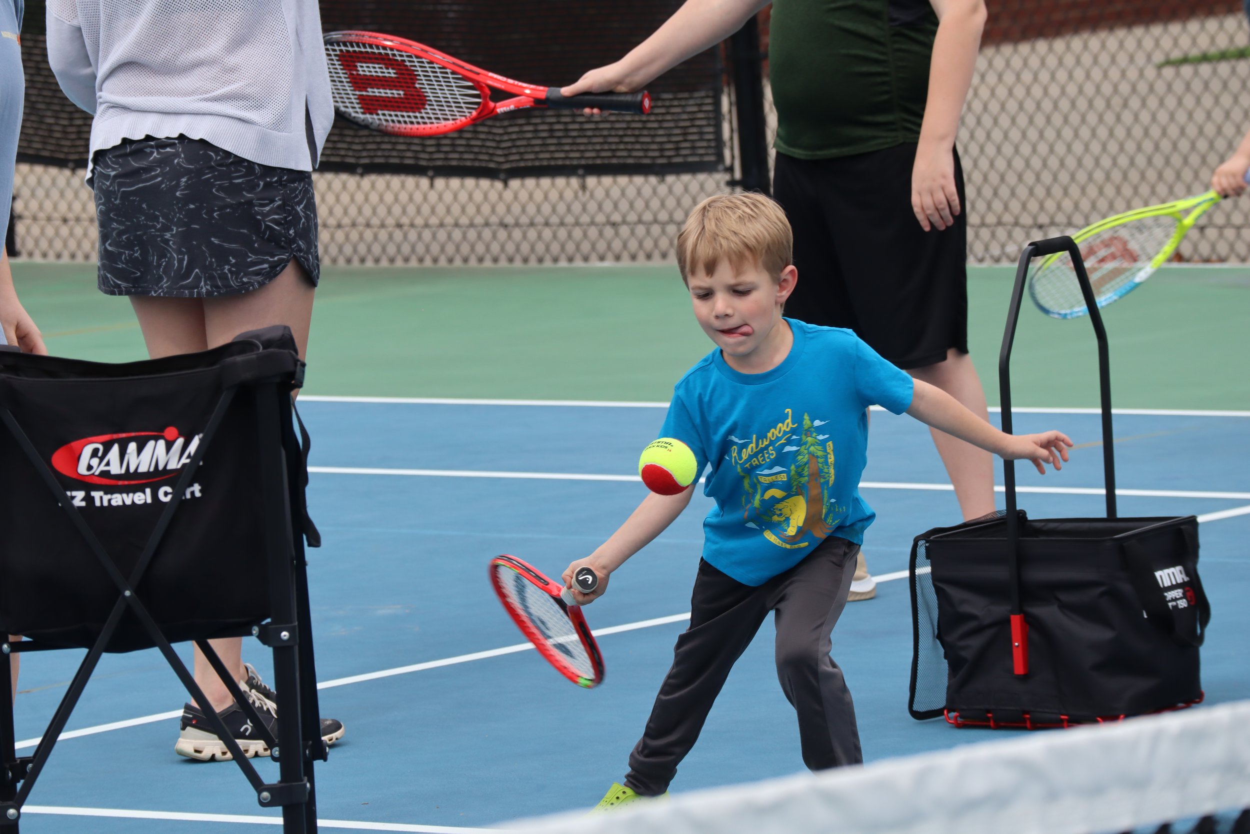boy in a blue shirt hitting a tennis ball