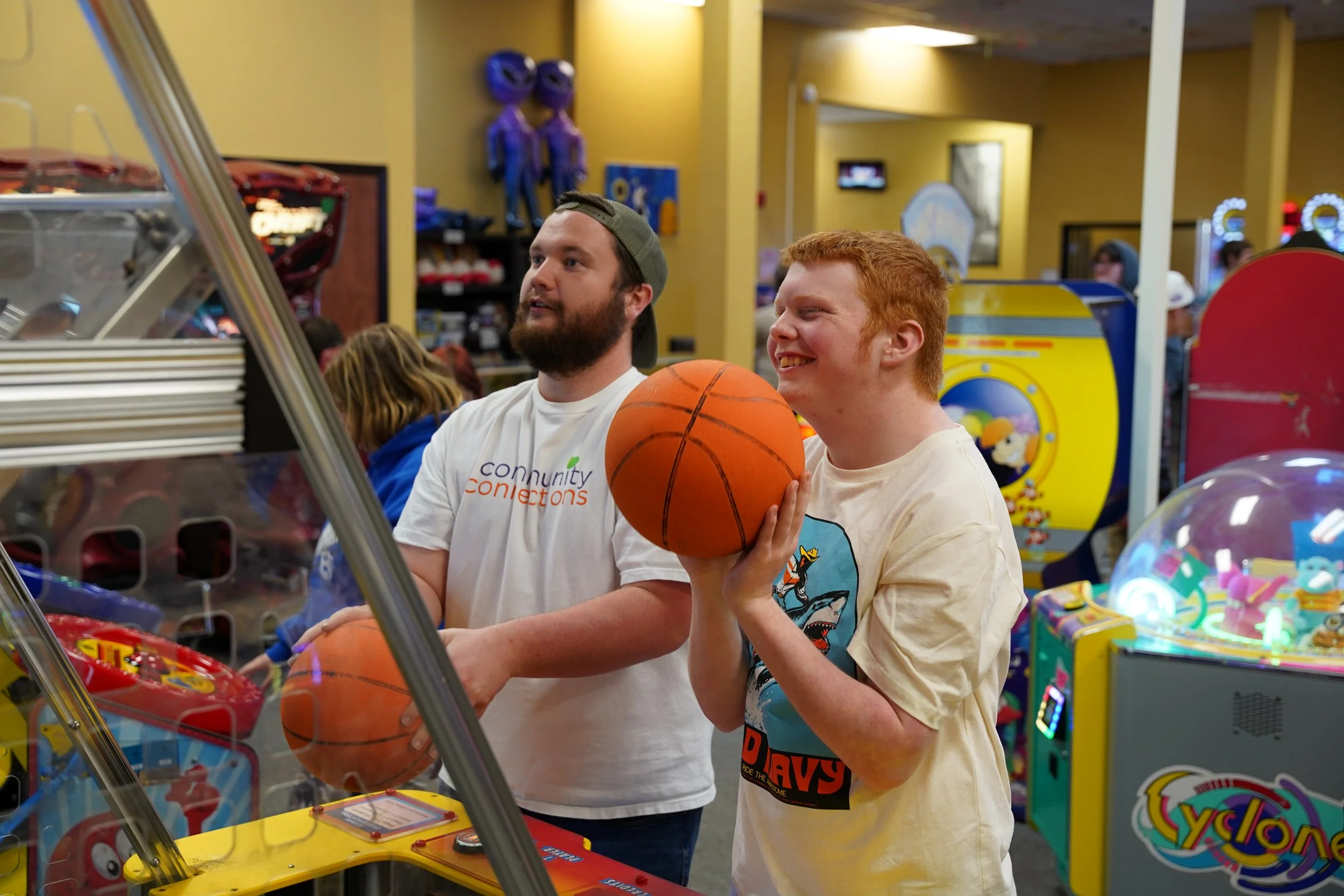 teenage boy and volunteer playing basketball arcade game