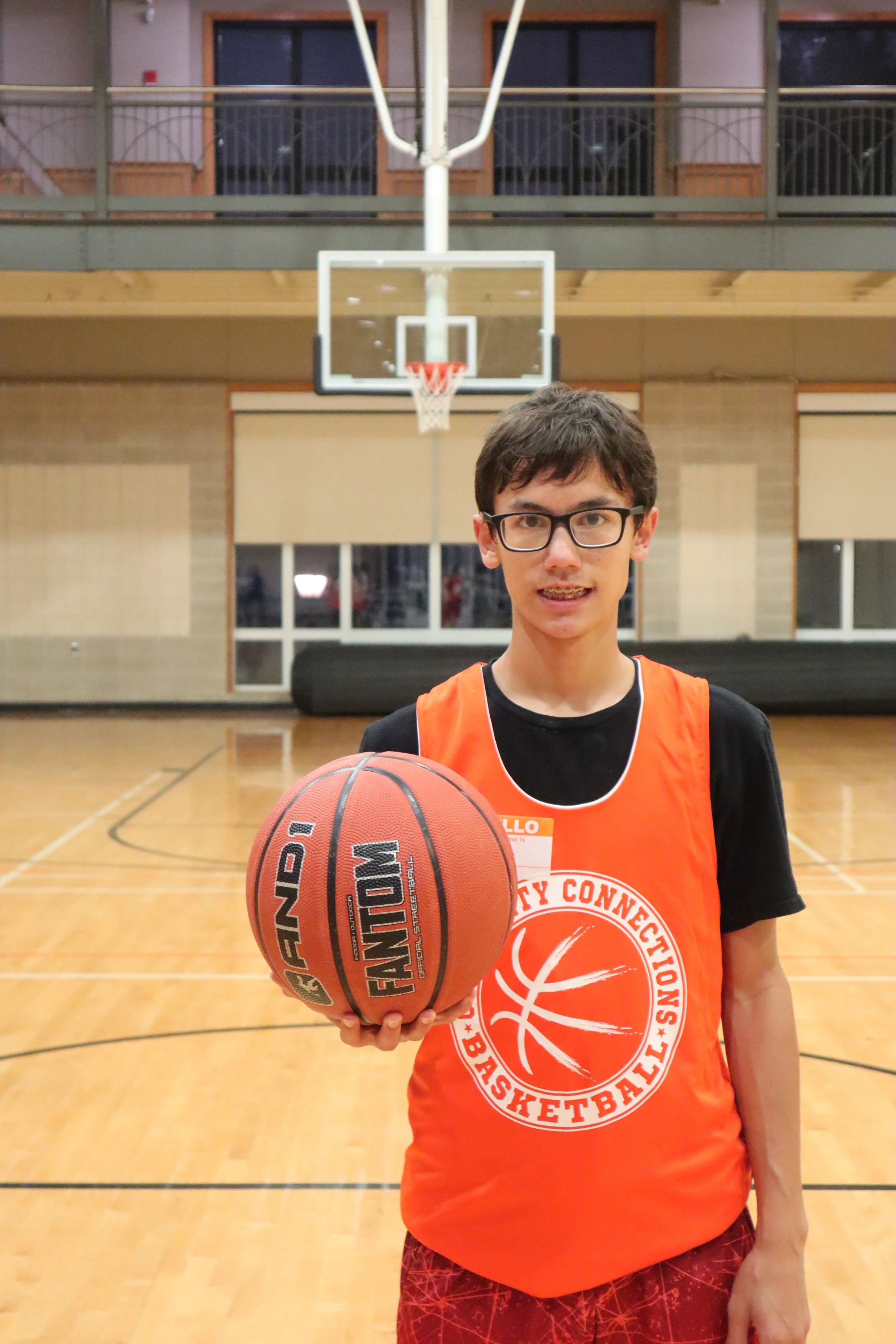 boy with an orange jersey posing with a basketball