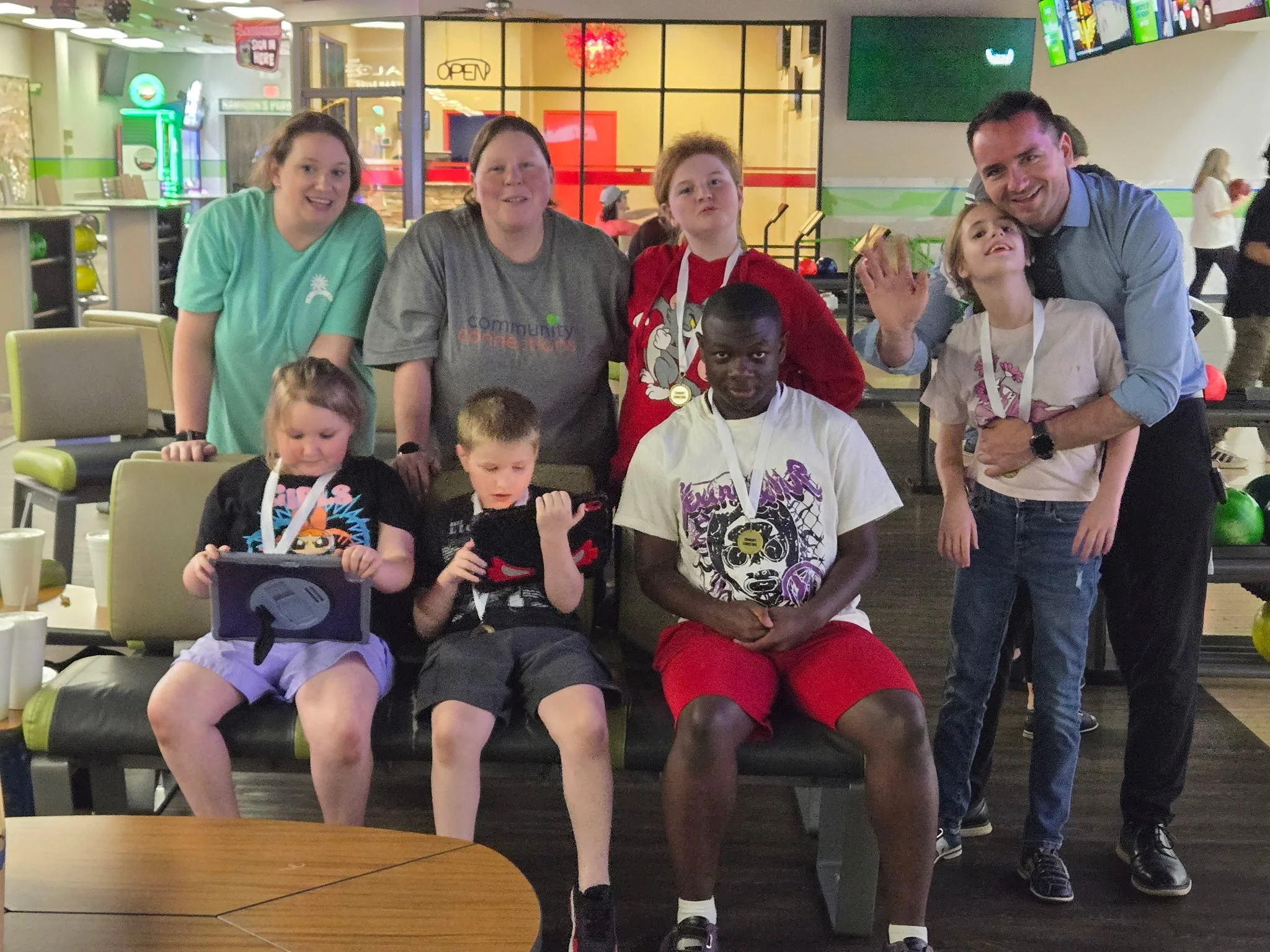 group of children & volunteers sitting in bowling alley