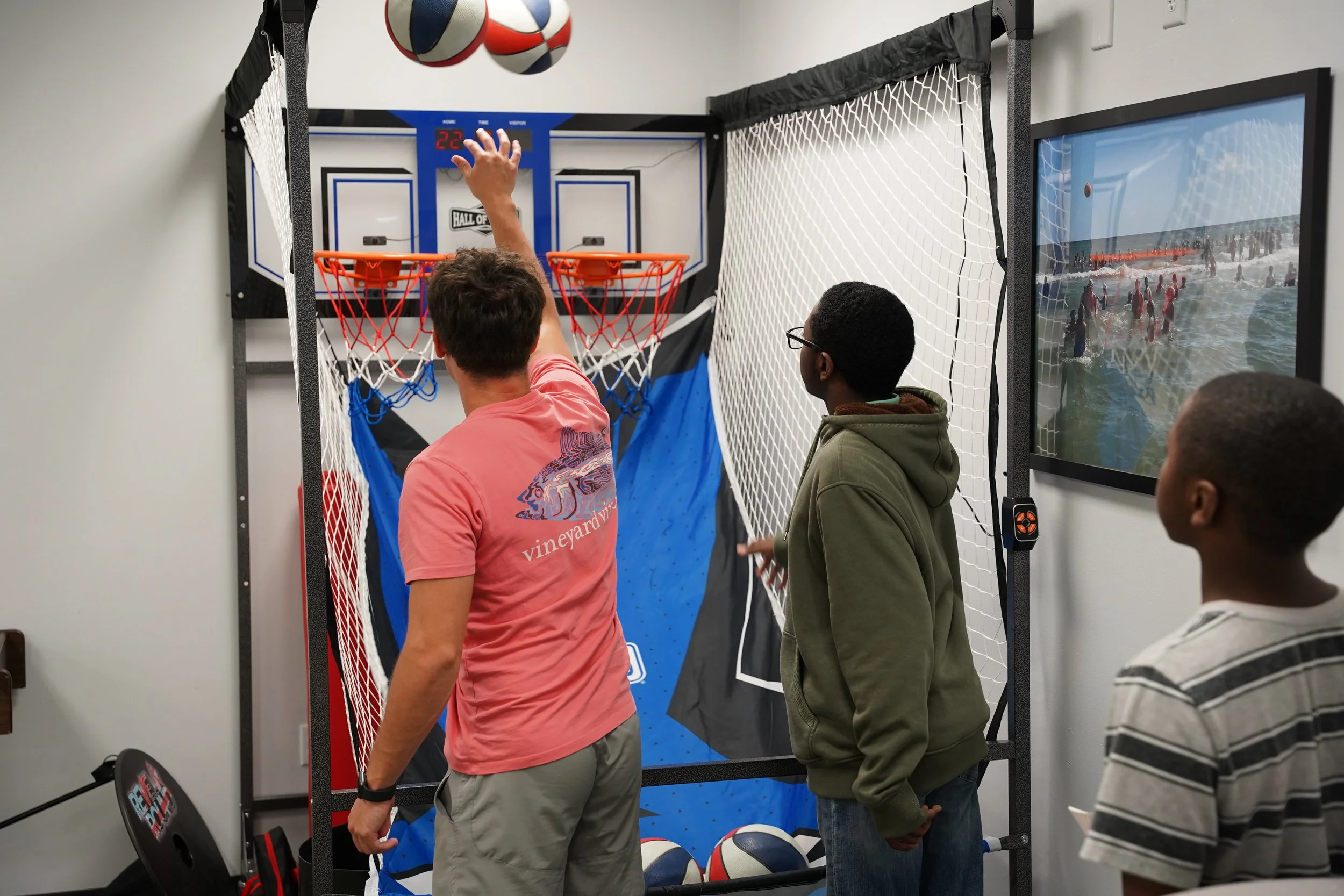 teenager & volunteer playing basketball arcade game
