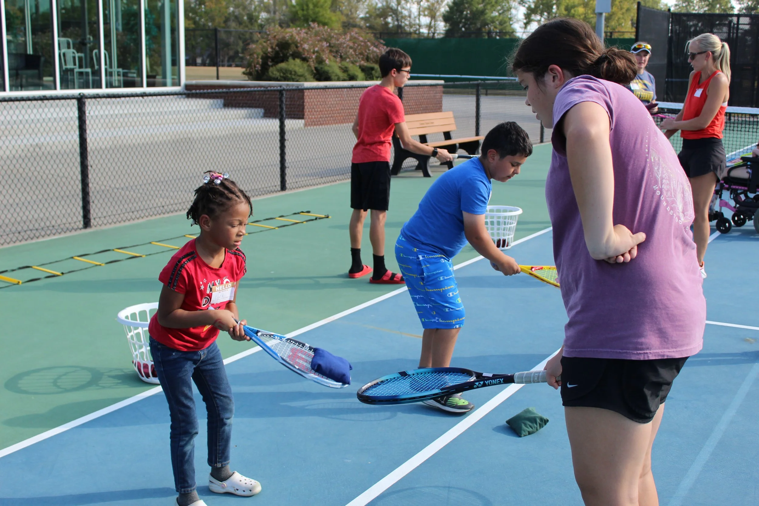 child and volunteer tossing a bean bag with tennis rackets
