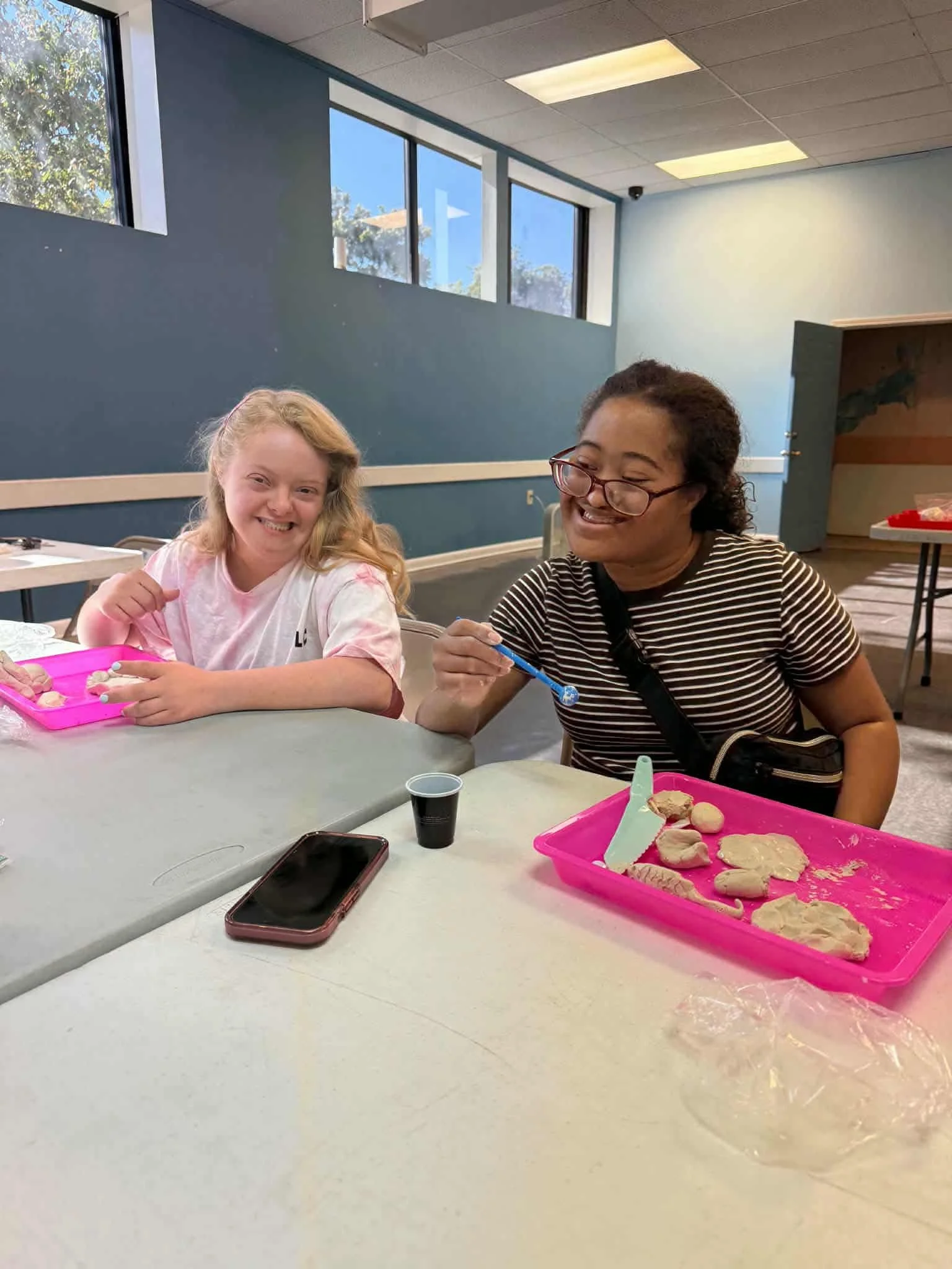  two girls smiling working on clay artwork