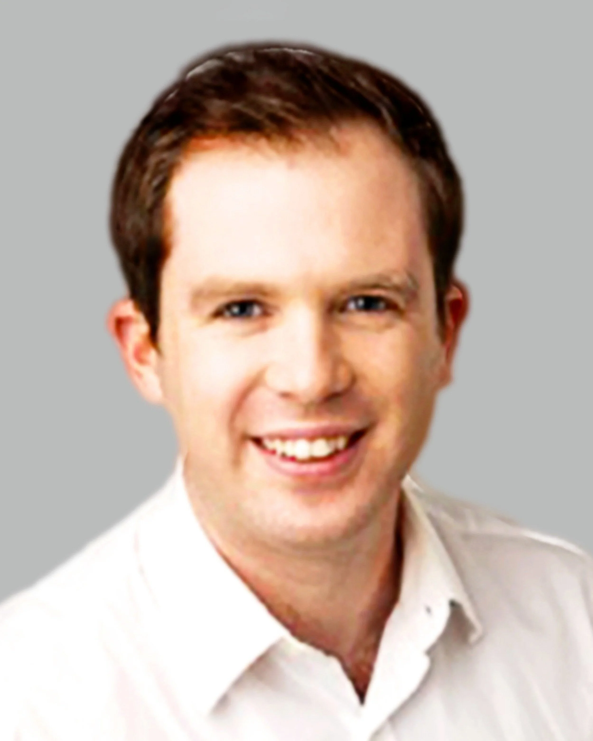 Headshot of a smiling man with brown hair and blue eyes, wearing a light-colored shirt against a gray background.