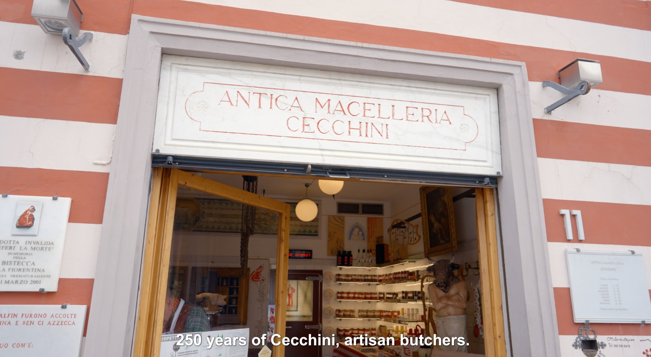 Exterior of Antica Macelleria Cecchini, an artisan butcher shop, with striped walls, signage, and interior view showcasing products and a sculpture. Subtitle reads "250 years of Cecchini, artisan butchers."
