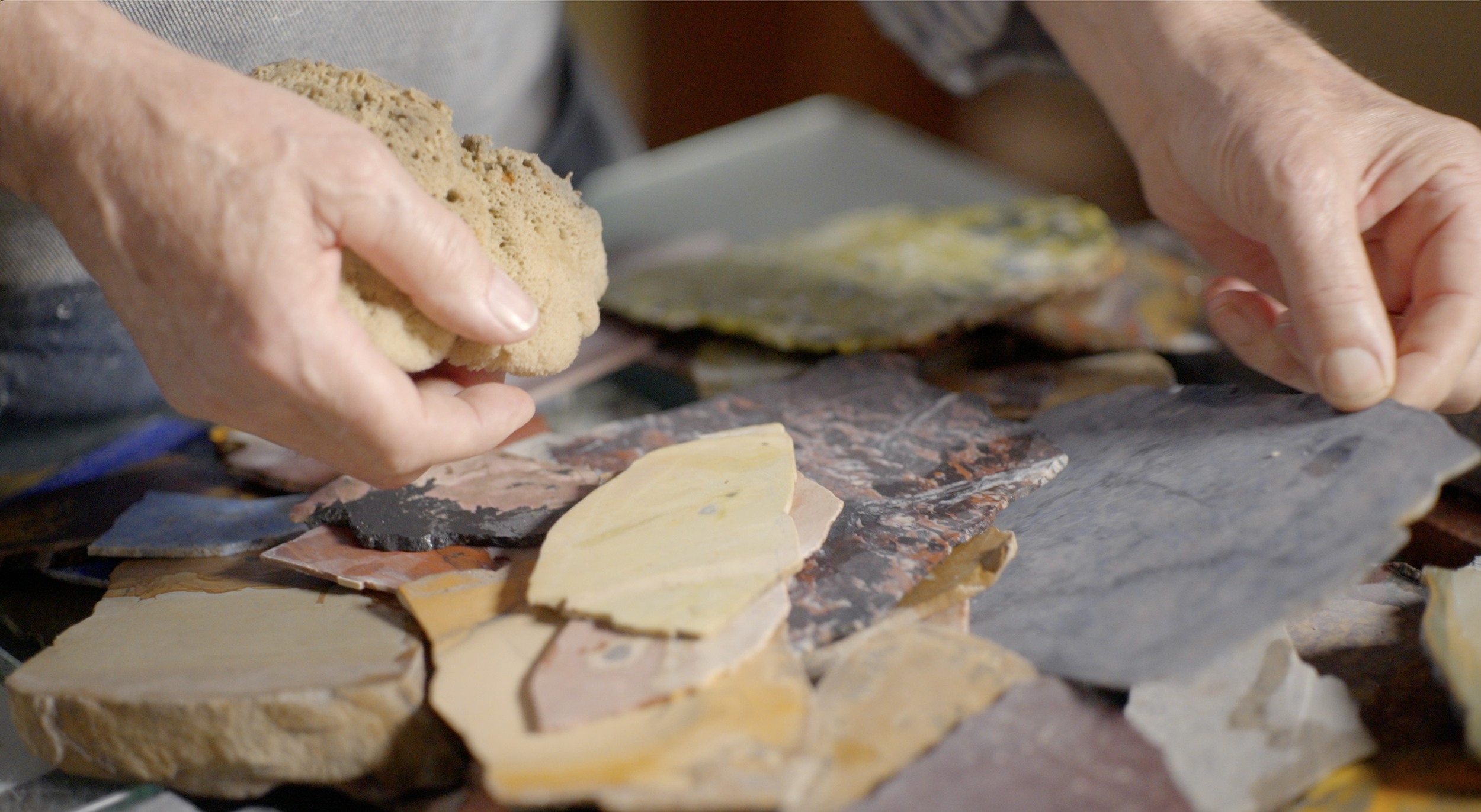 Hands holding various types of stones and minerals.