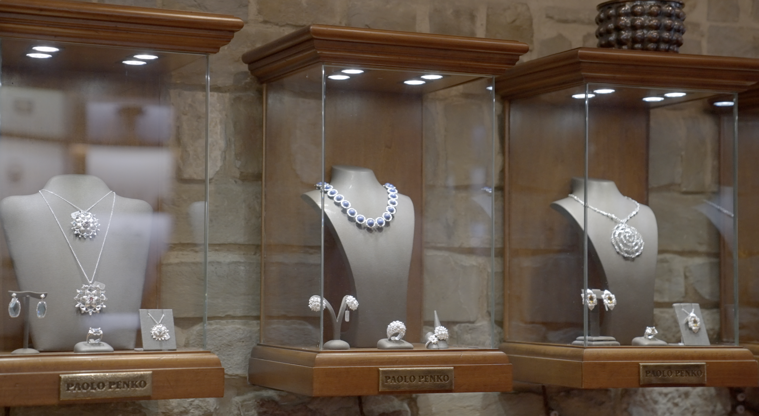 Jewelry display with necklaces, earrings, and rings in glass cases at a store.