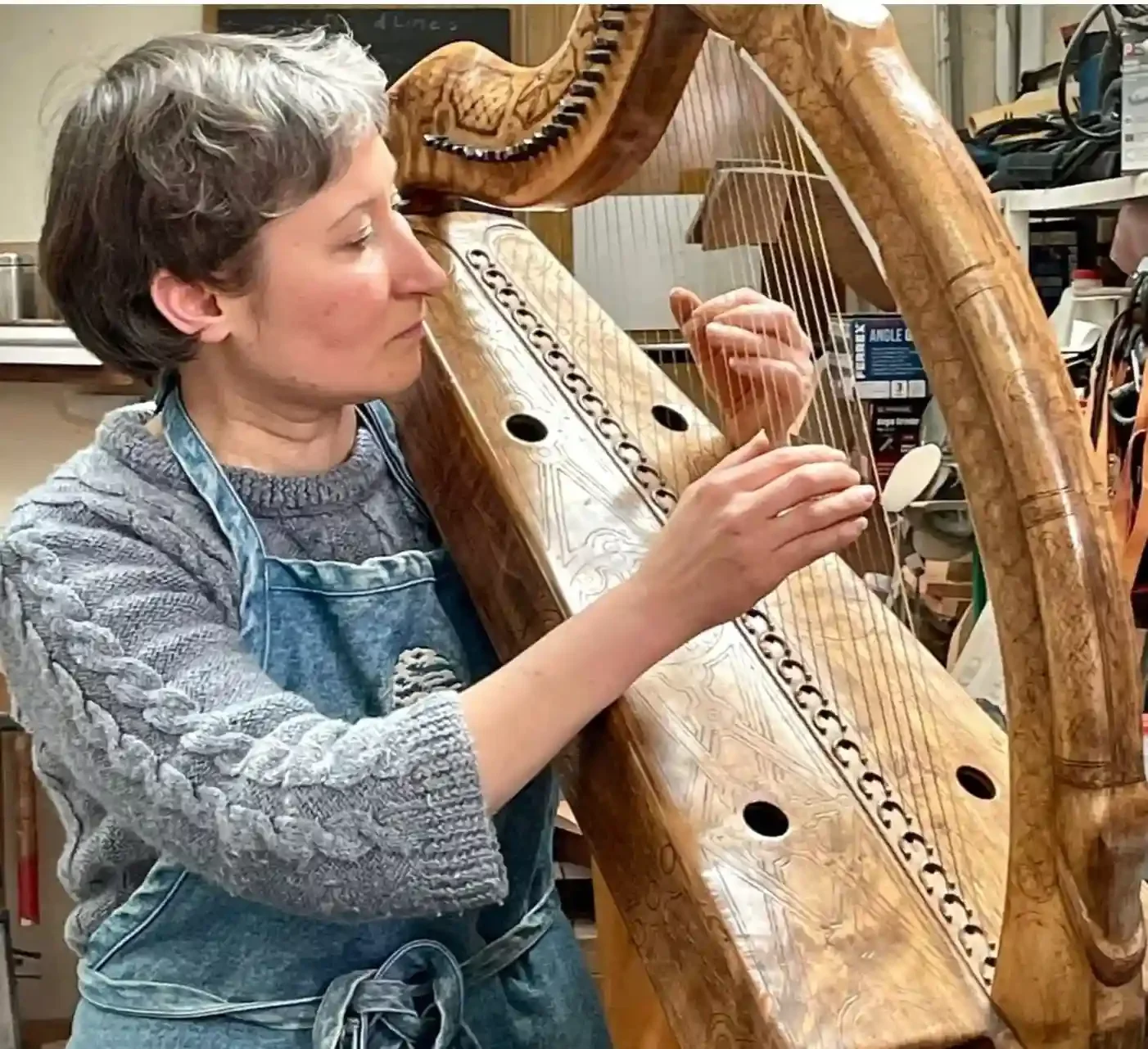 Person playing a wooden harp in a workshop.