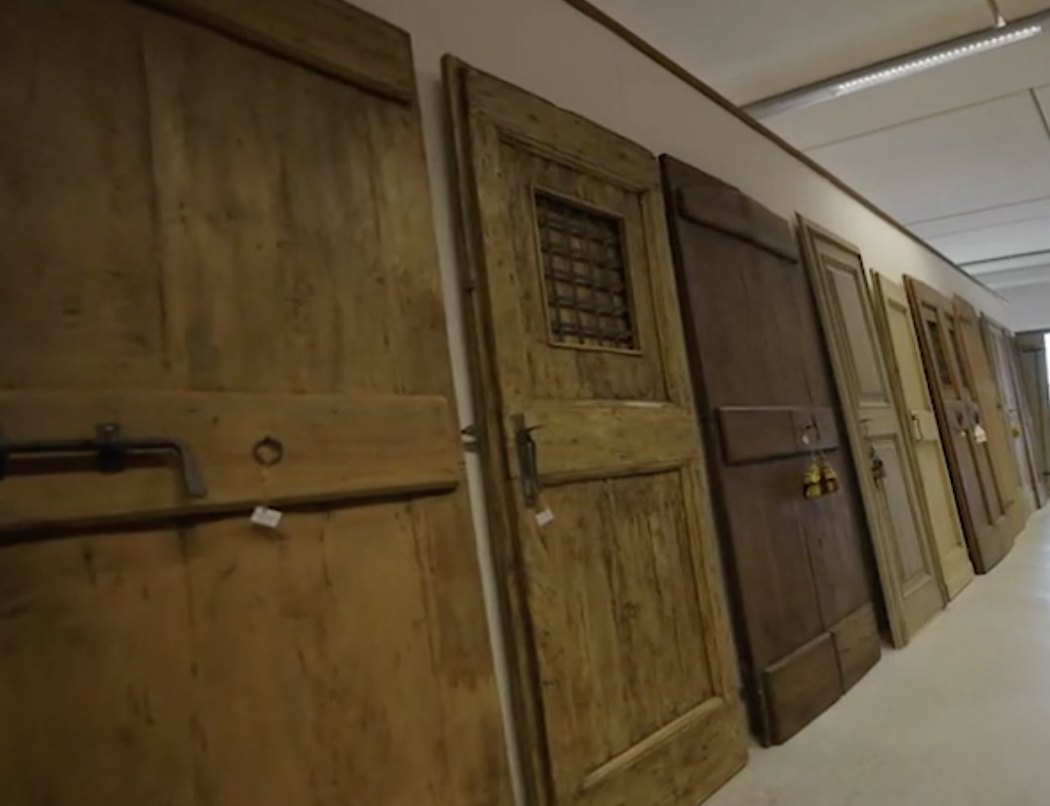 Row of vintage wooden doors displayed against a wall indoors