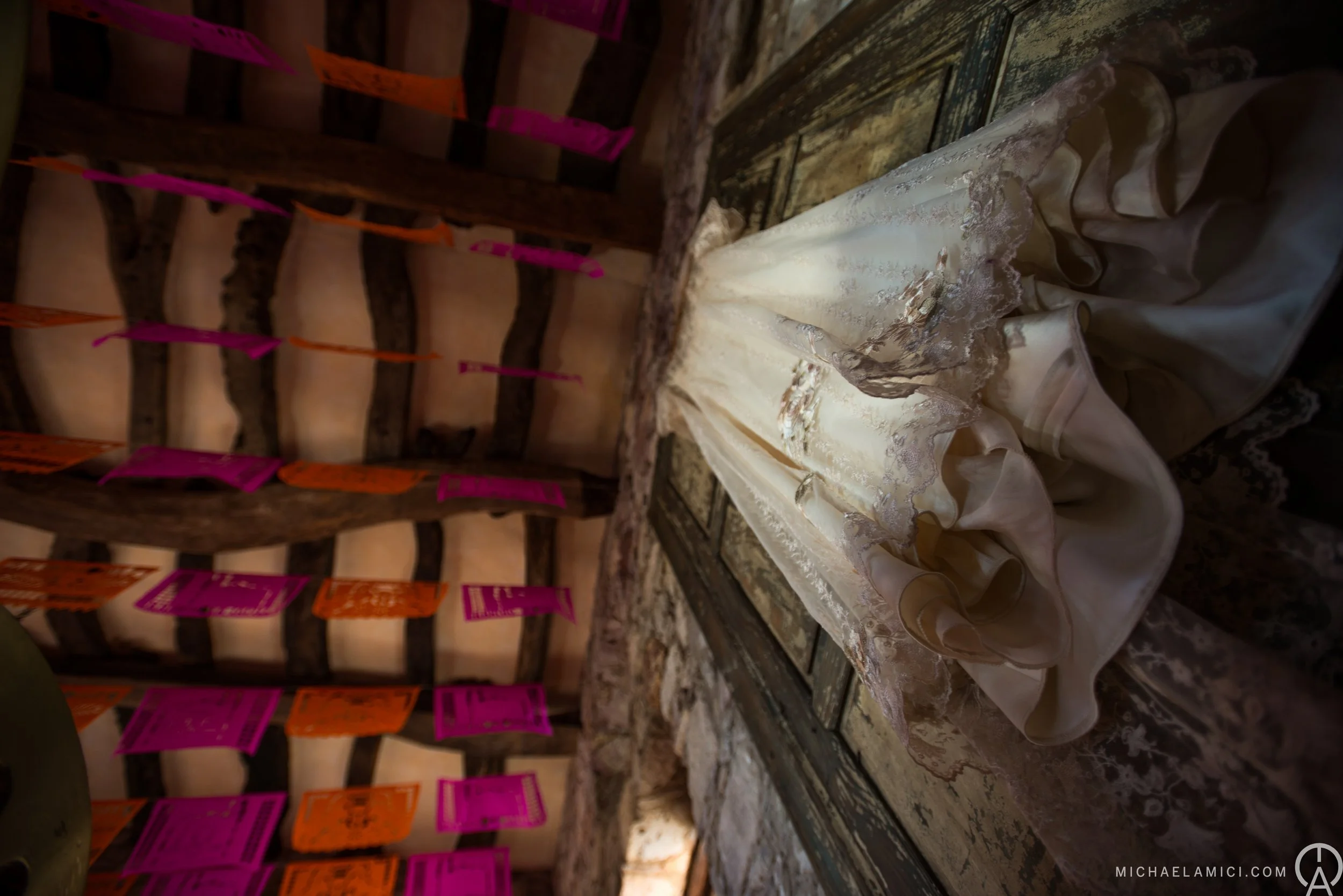 A close-up of a delicate, vintage-style wedding veil with lace and embroidery details, draped over an antique wooden table.