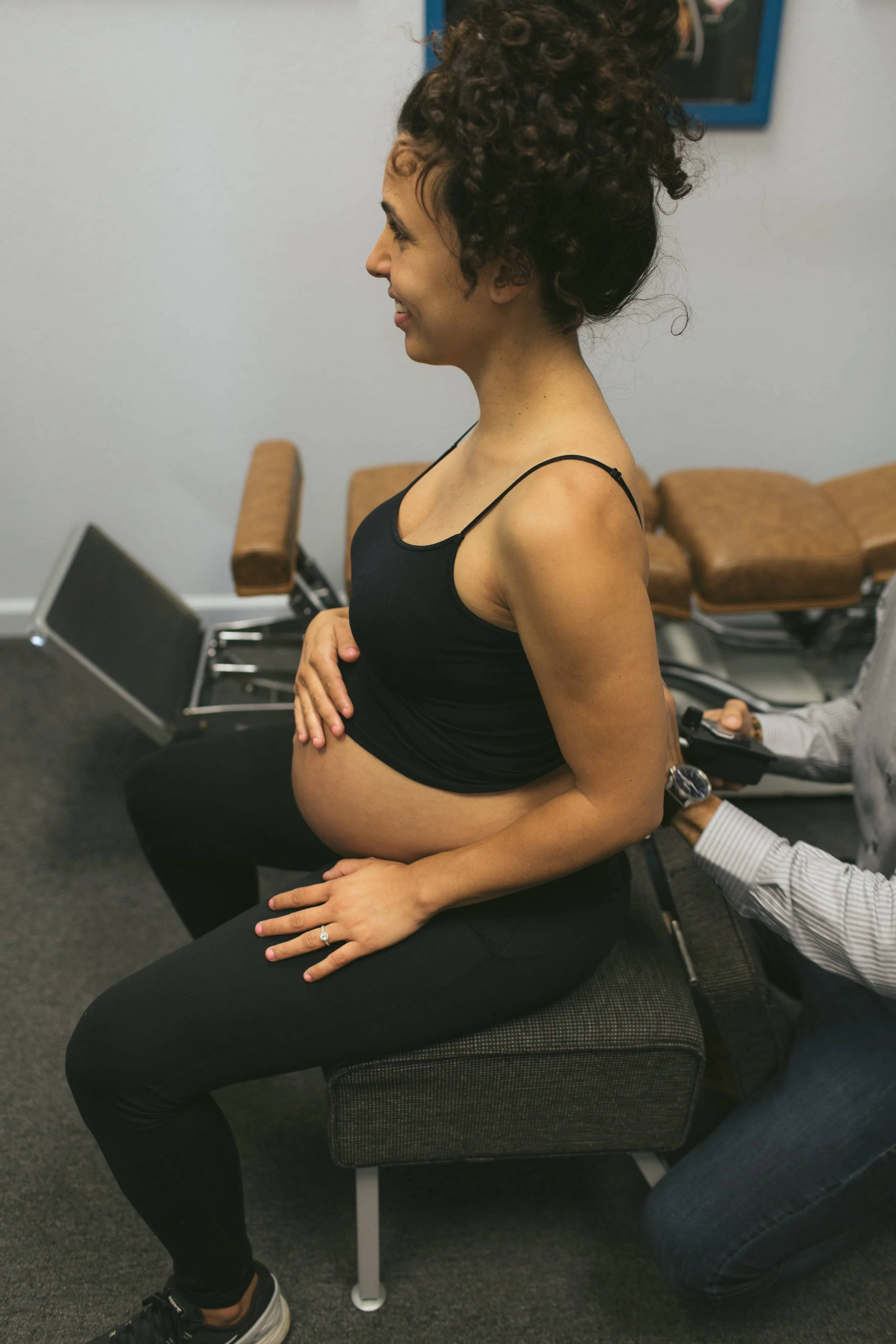 Pregnant woman sitting in a medical office, undergoing a pregnancy ultrasound exam.