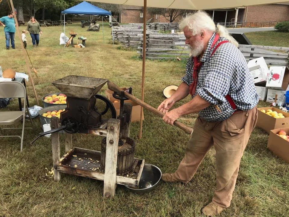 Man using an antique apple cider press outdoors