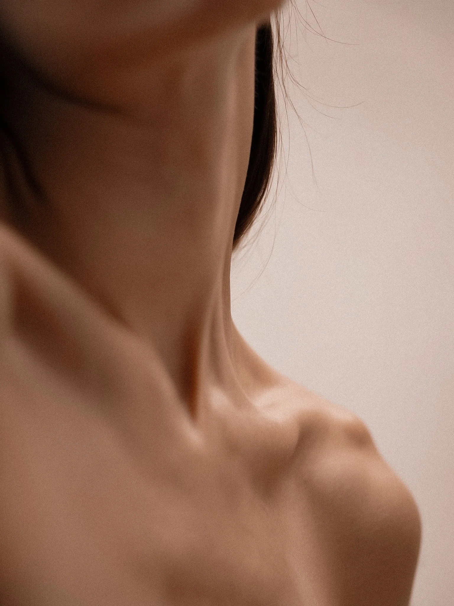 Close-up of a person's neck and shoulder, with smooth skin and a hint of collarbone visible.