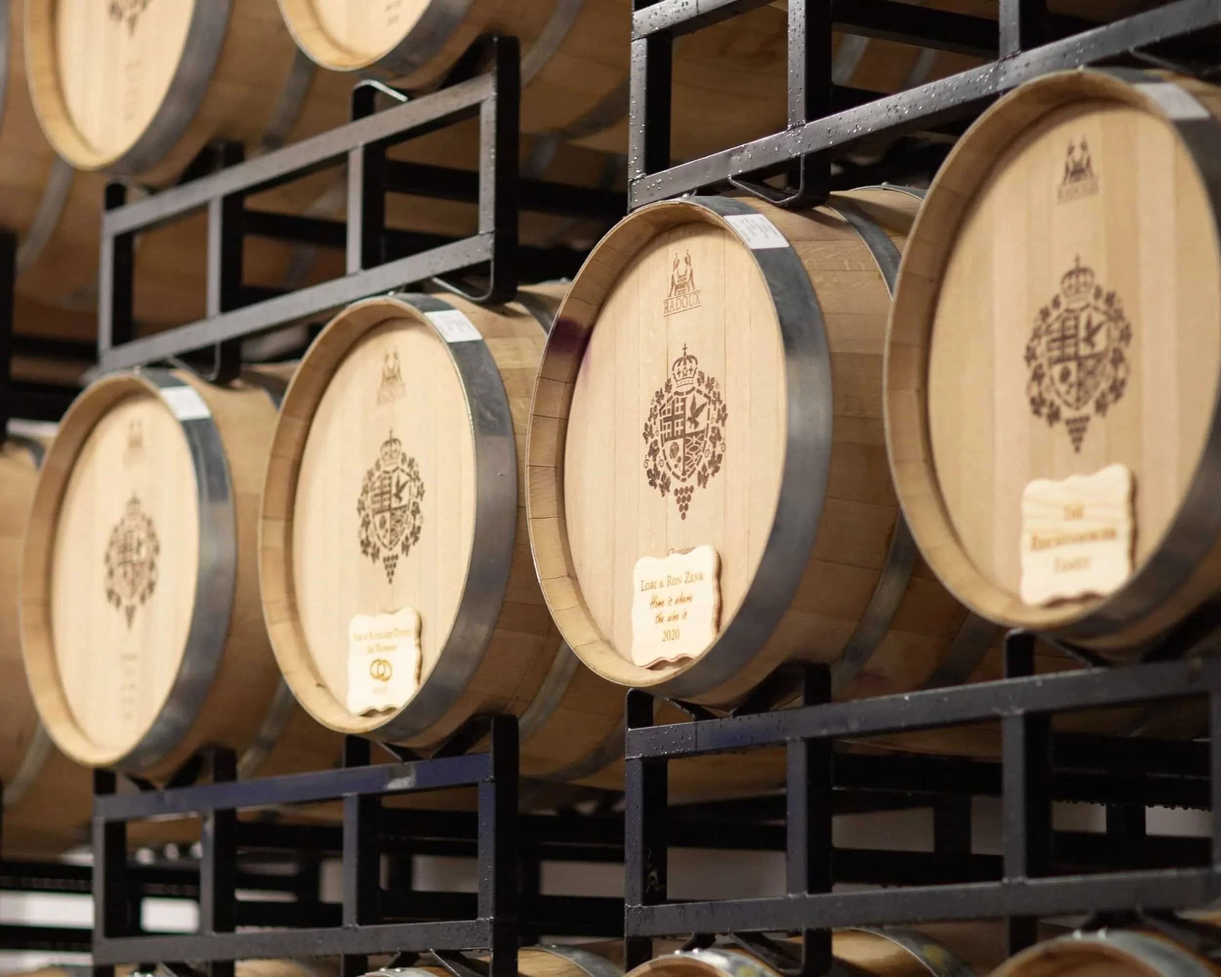 Row of wooden barrels with metal bands stored on racks in a cellar.