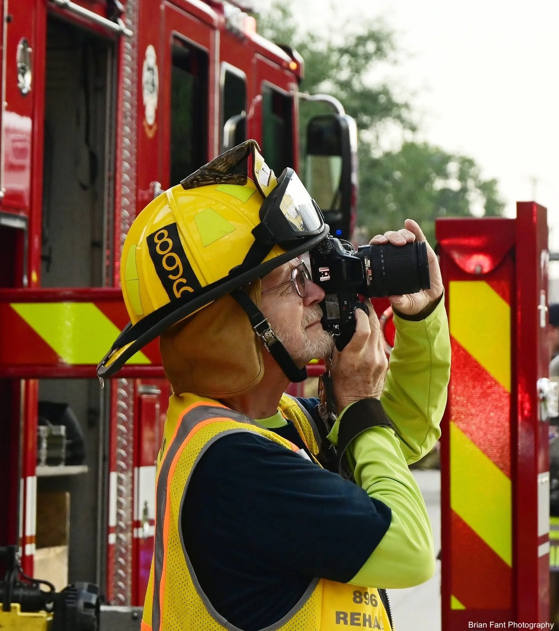 Man wearing helmet with 896 on the side take a photograph in front of a fire truck