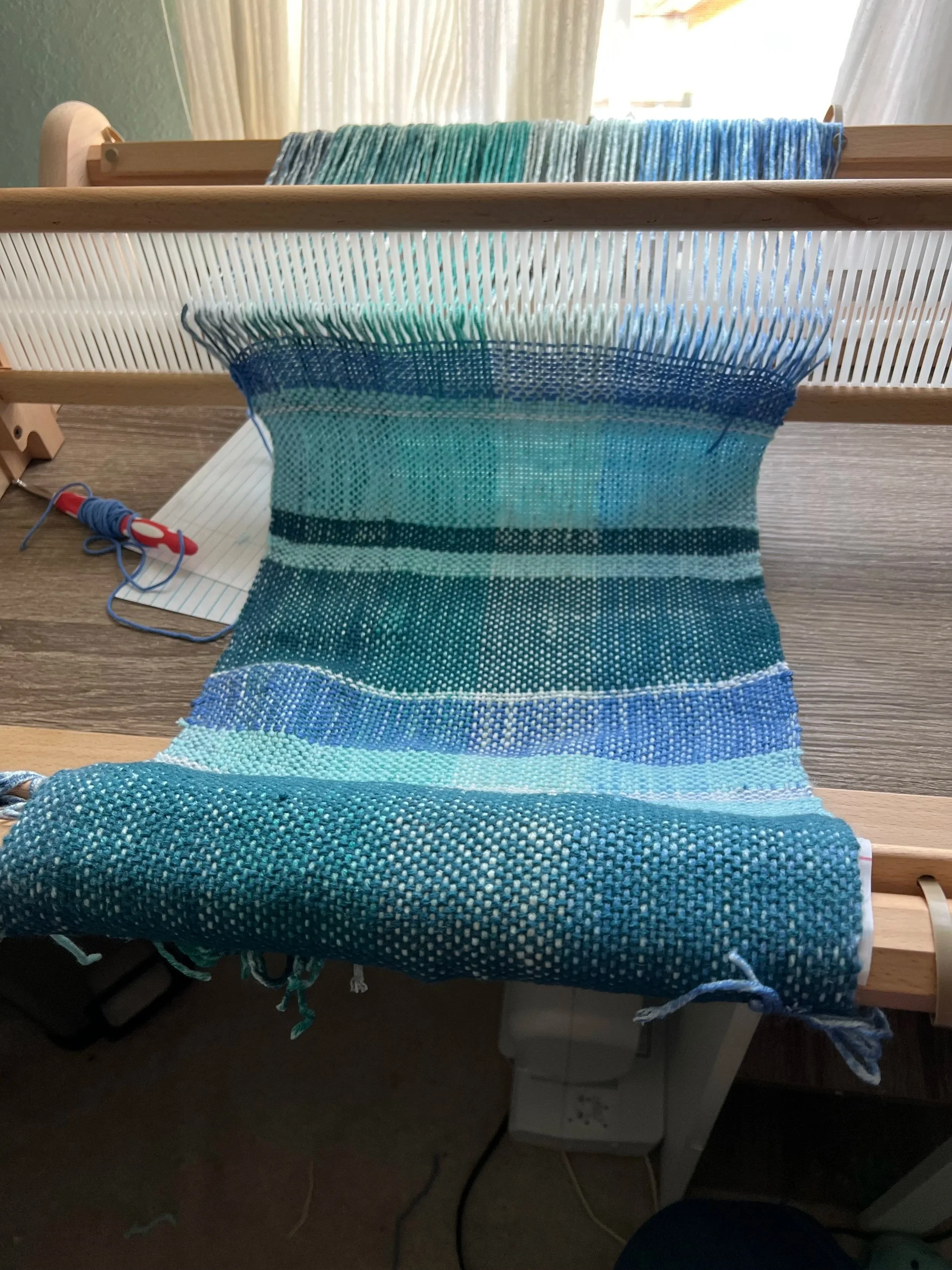 Rigid heddle loom with woven material