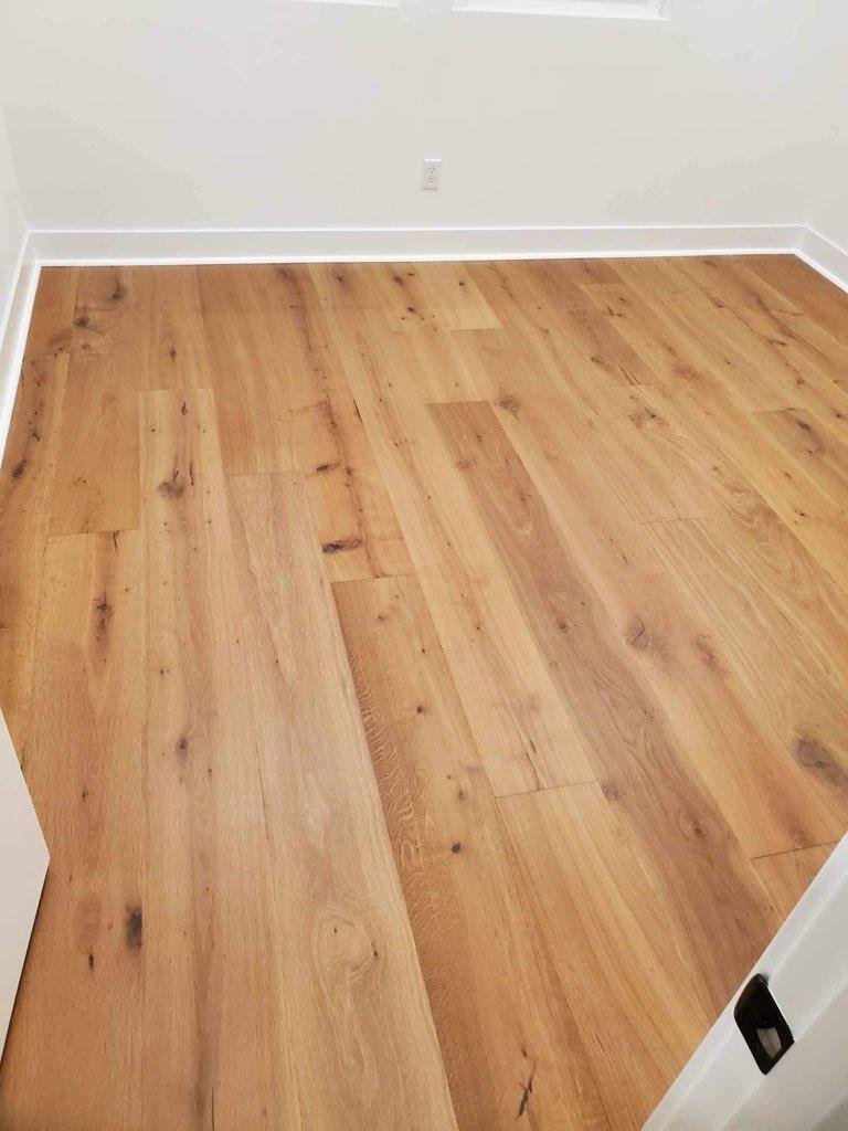 Empty room with light wood laminate flooring and white walls.