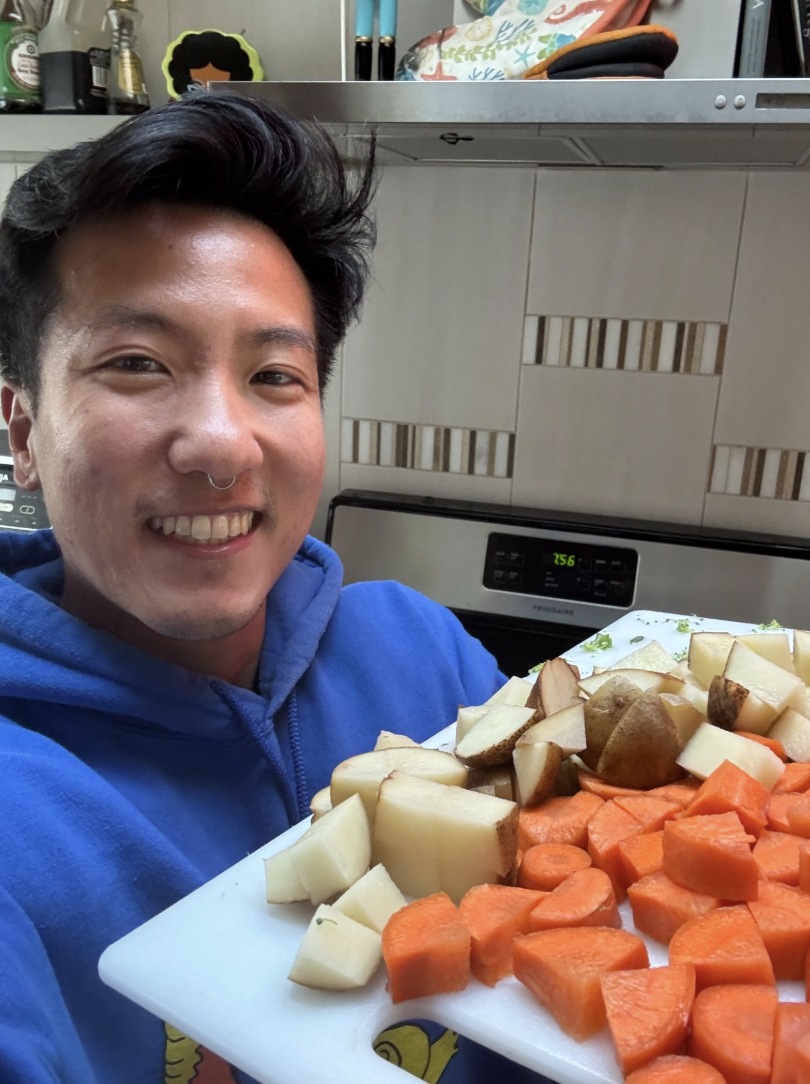 Landyn Pan holding a cutting board of chopped sweet potatoes and potatoes for meal prep