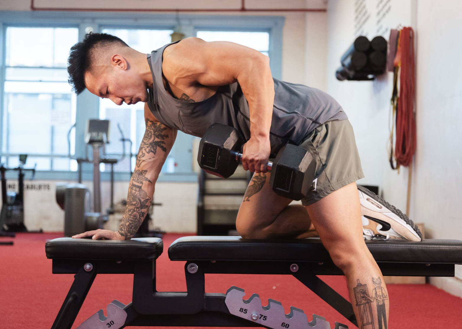 Person performing a bent-over dumbbell row on a gym bench, working through beginner gym anxiety at their own pace.
