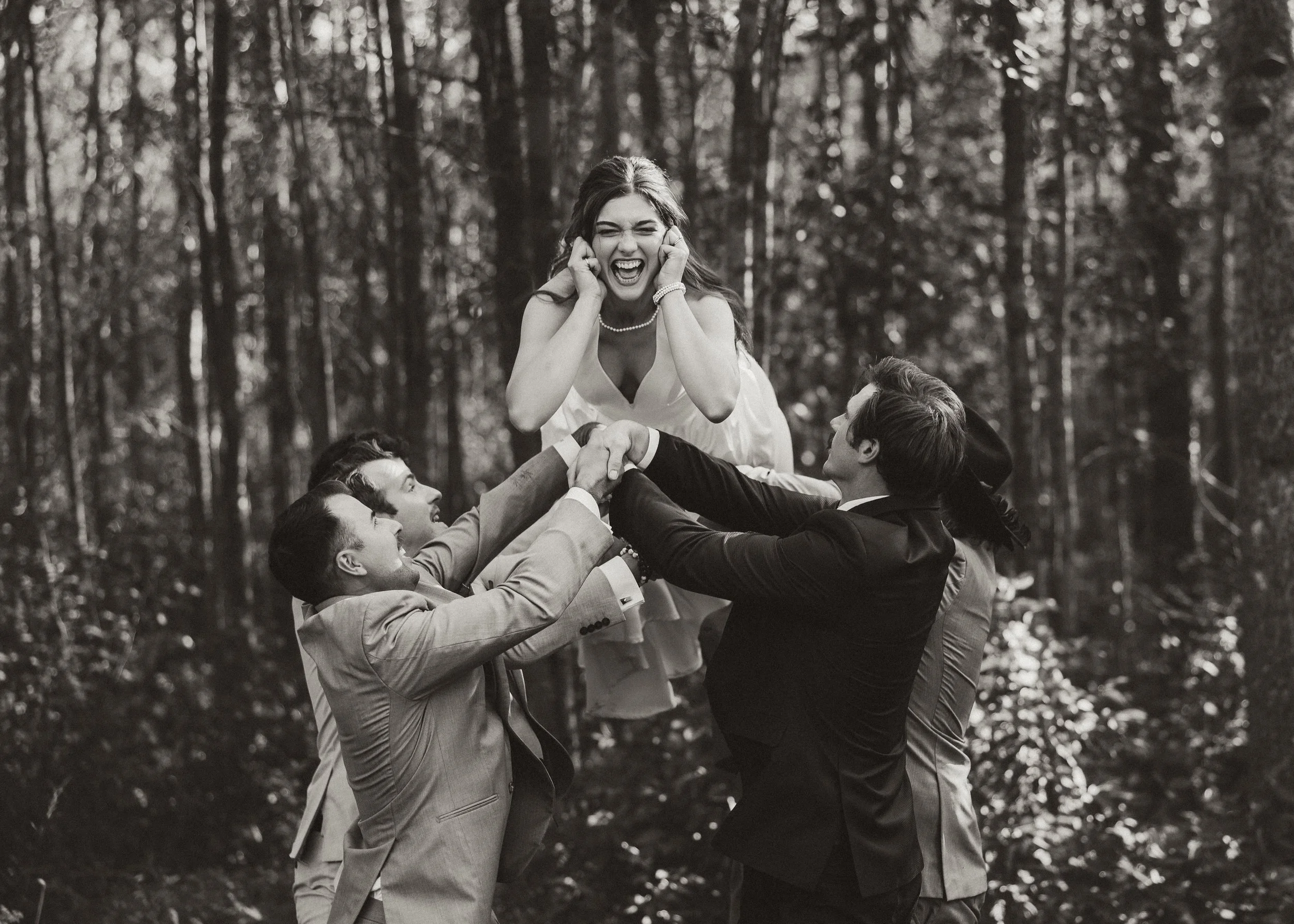 bride is tossed in the air by groomsmen