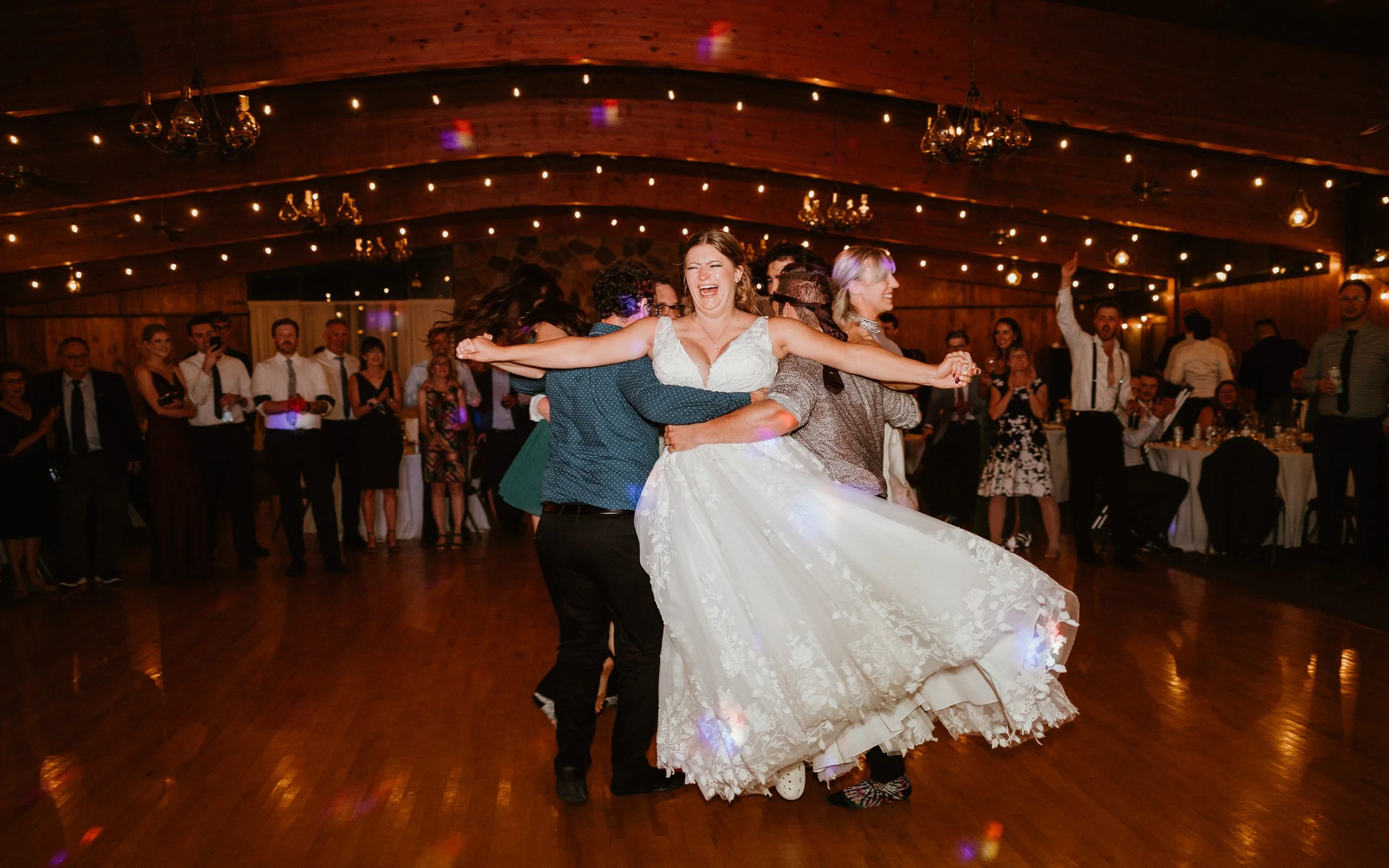 bride and groom laughing on mountain as snow falls