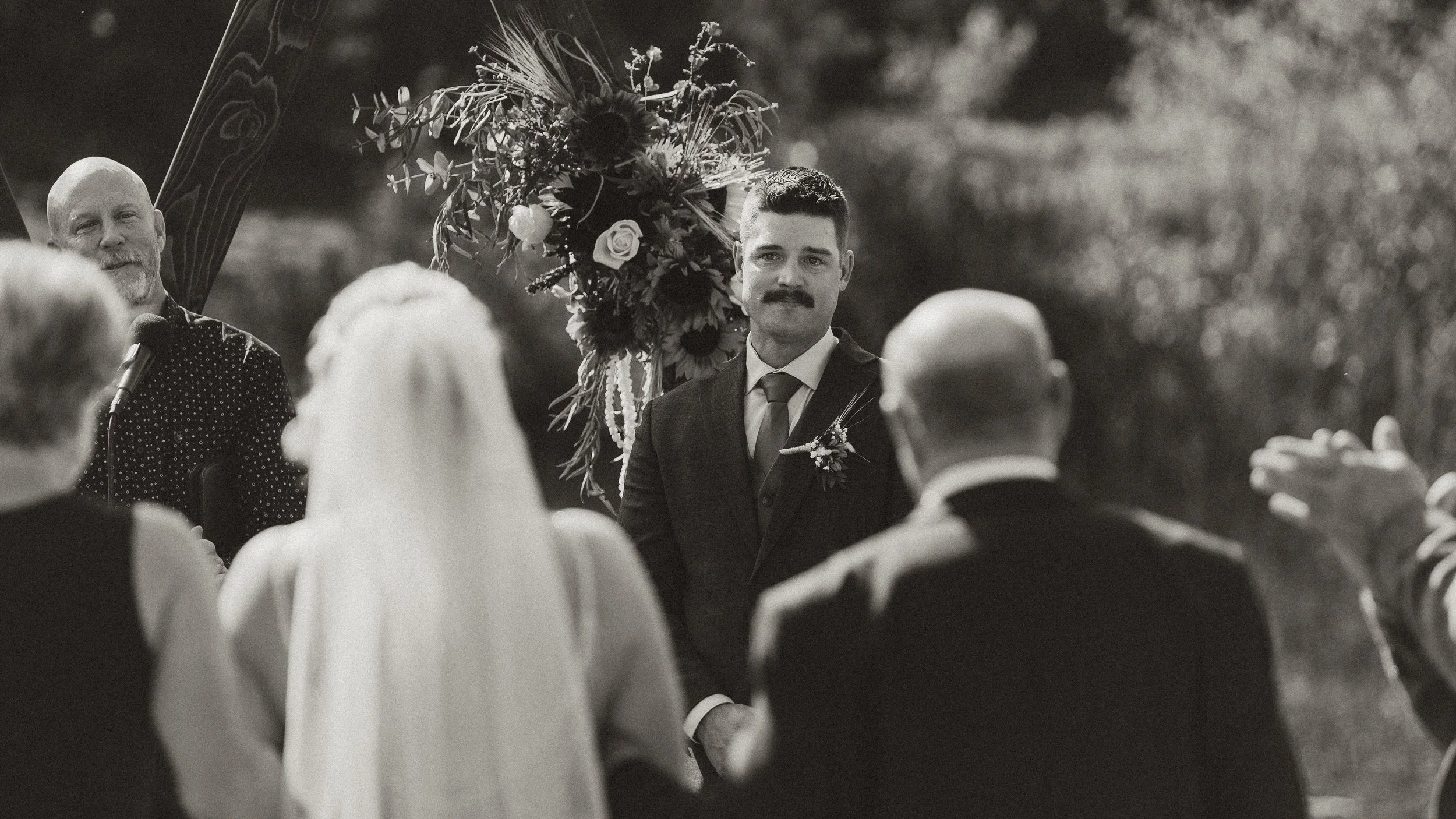 Groom watching his bride walk down the aisle with her parents