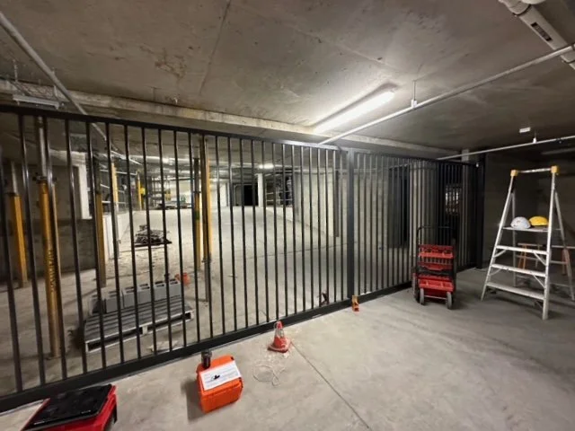 Underground parking garage with metal gate, construction tools, and safety equipment