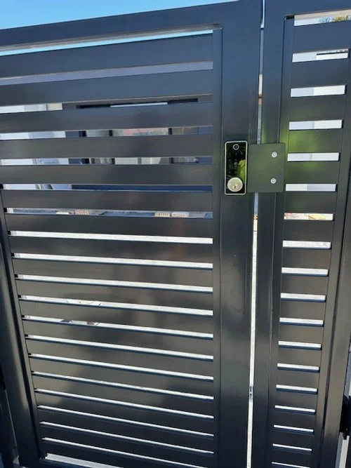 A black metal gate with horizontal slats and a digital lock and keypad.