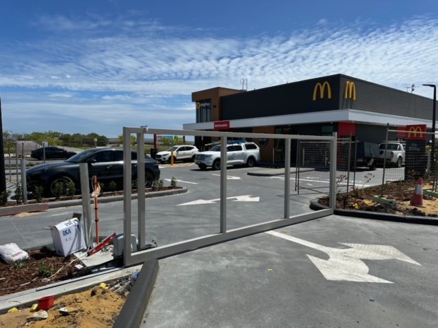 McDonald's restaurant with a parking lot and a temporary metal barrier in the foreground.
