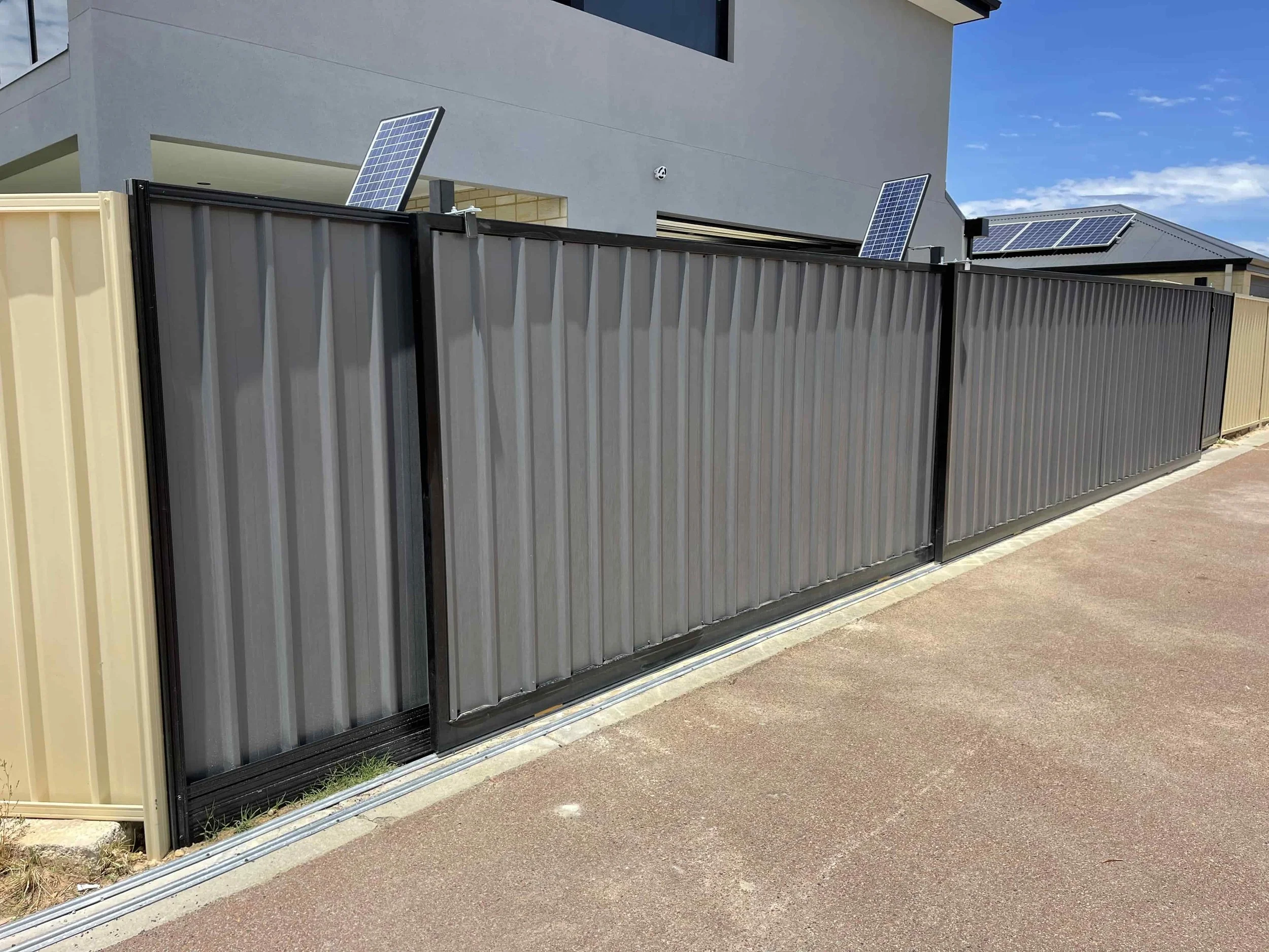 A modern metal fence with solar panels on top of the posts.