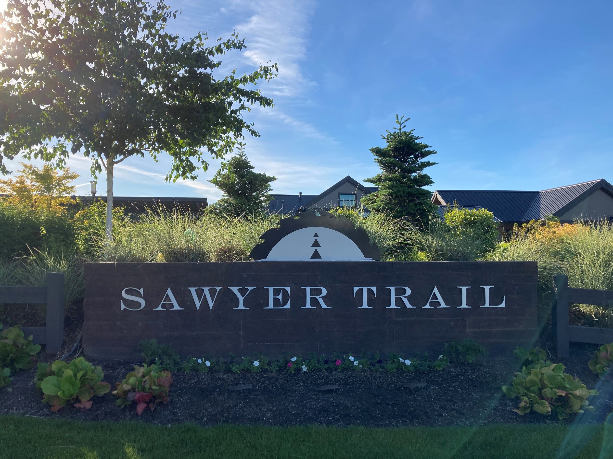 Community monument sign for Sawyer Trail with beautiful landscaping including bark, bushes, and grass