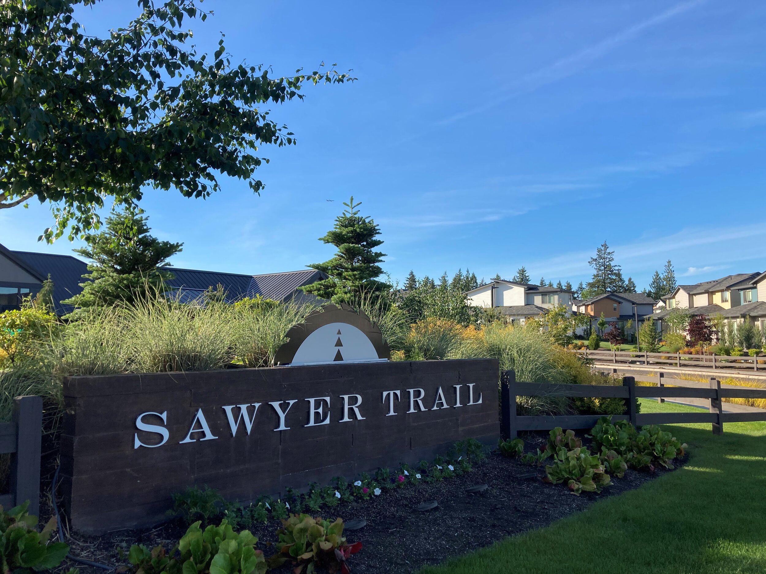 Brick sign for Sawyer Trail community with split rail fence and houses in the background