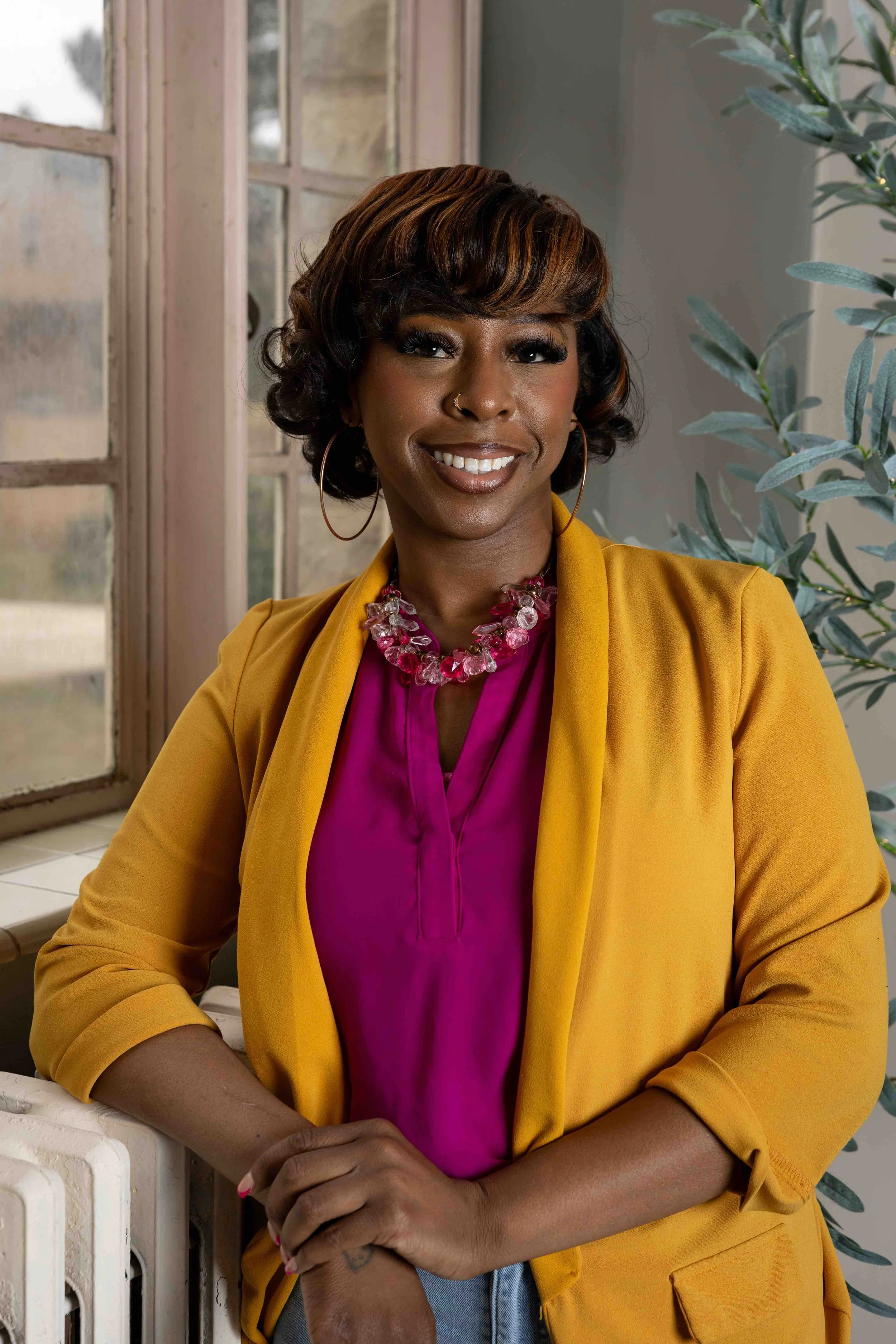 A smiling woman in front of a window smiling for her portrait by Lindsay Stayton Photography