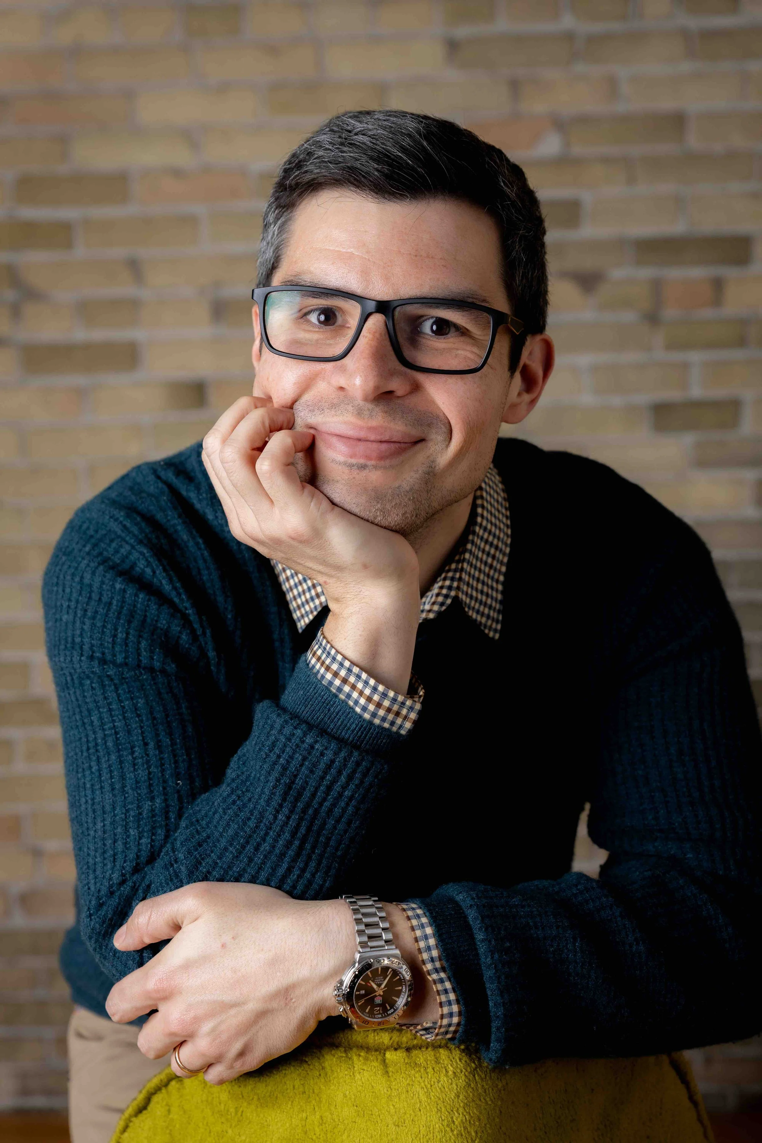 A smiling man infront of cream city brick in Lindsay Stayton's Third Ward Milwaukee Studio