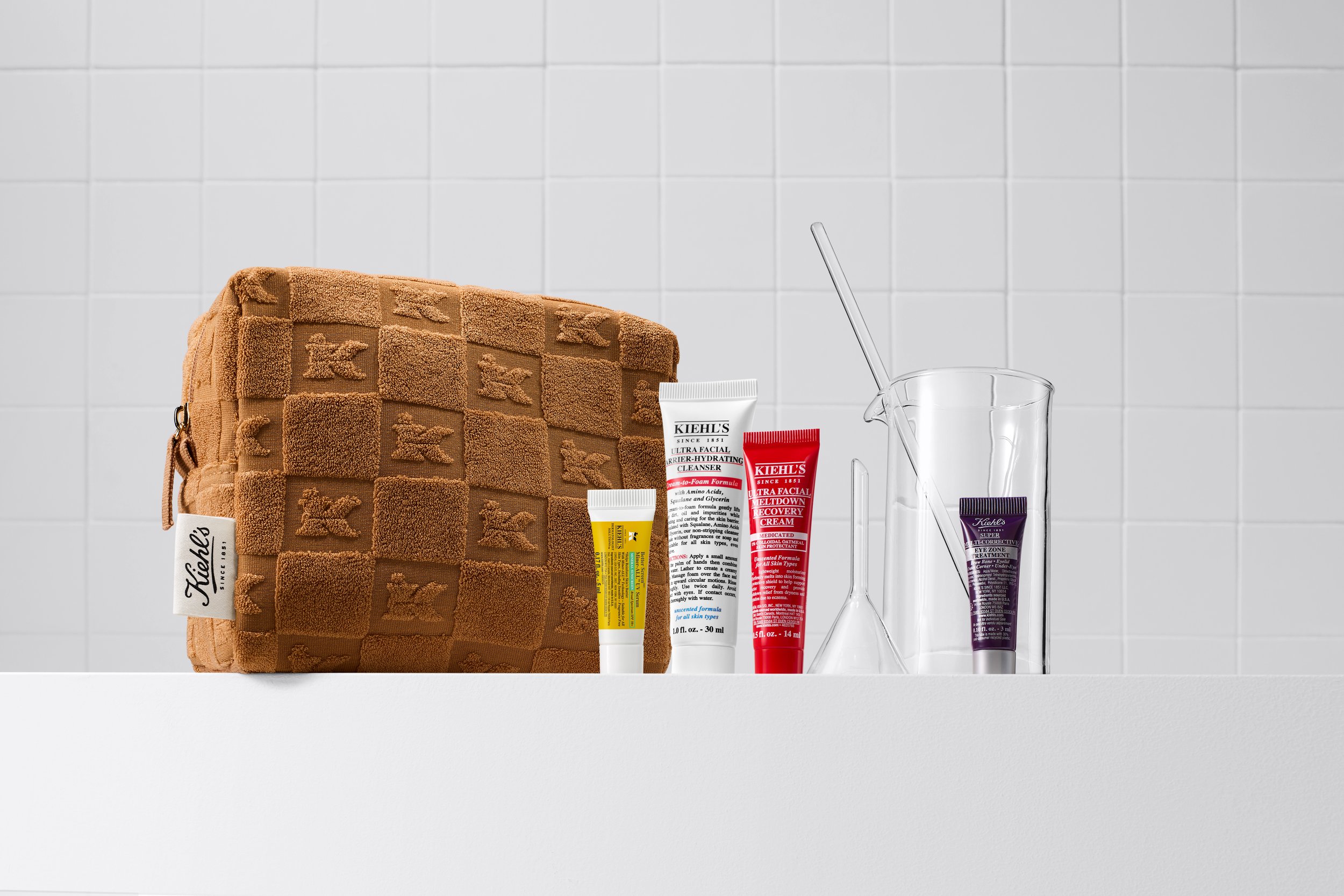 Kiehl's gift-with-purchase bag and travel-size products on a white tile ledge