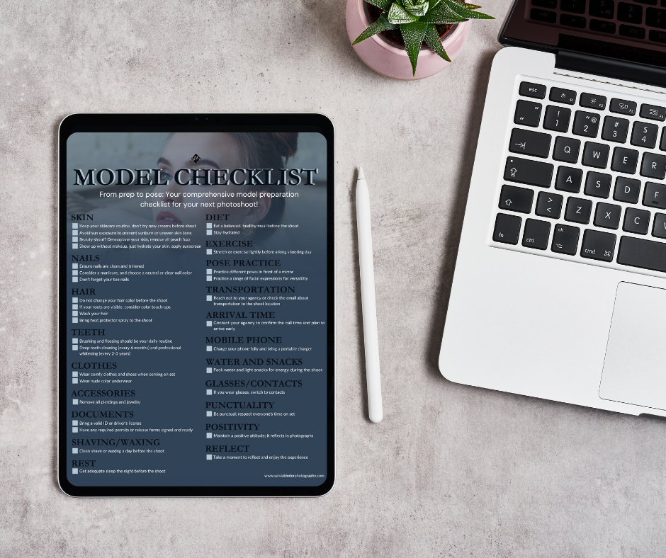 A model checklist on a tablet, a white stylus, a laptop, a pink pot with a green plant, and part of another laptop on a concrete surface.