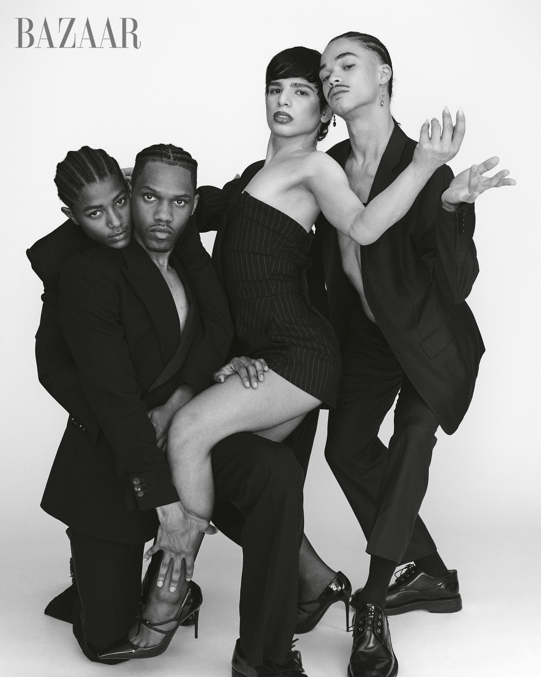 Black and white photo of four fashionably dressed models posing together against a plain background, with the 'Harper's Bazaar' logo in the top left corner.