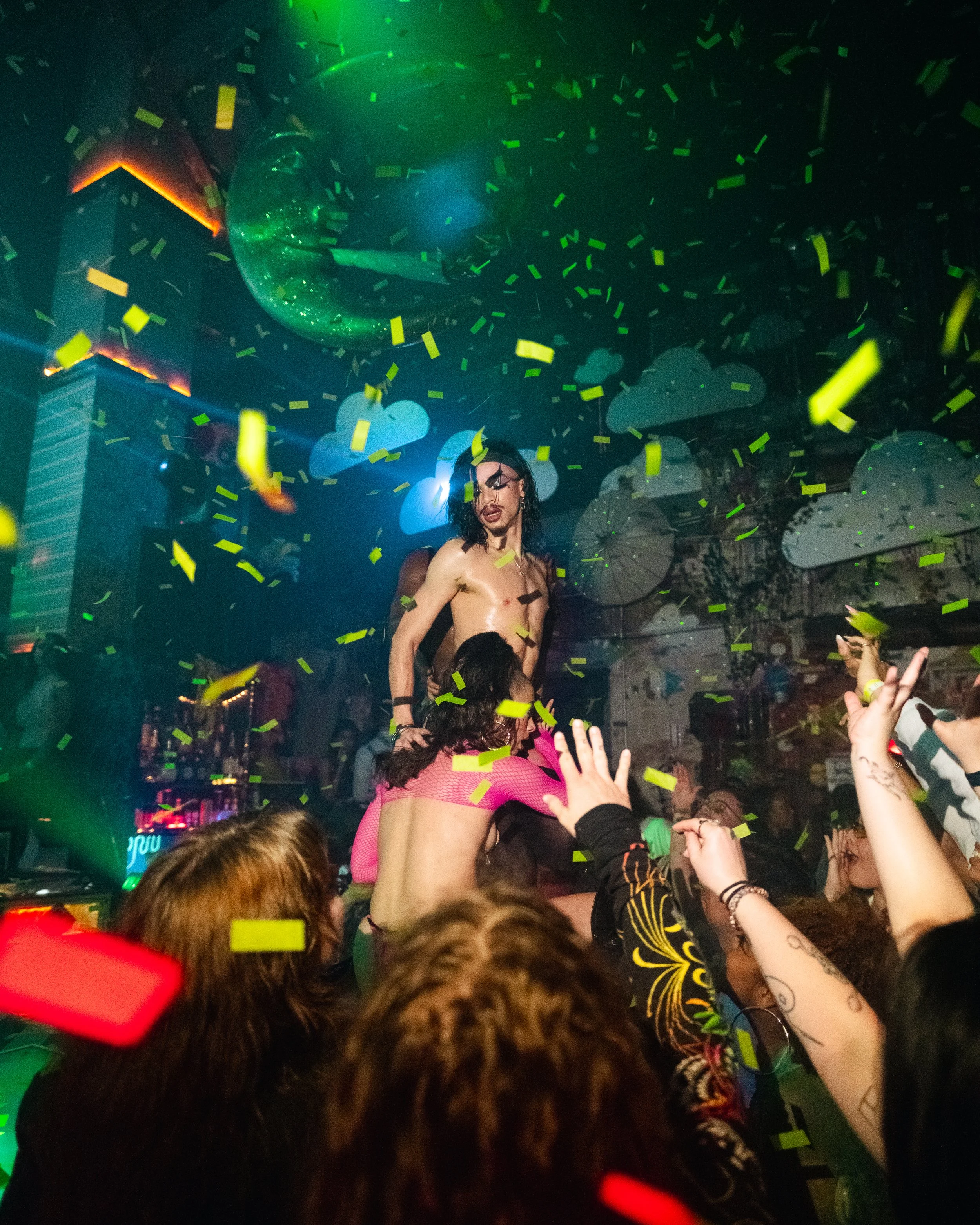 A lively party scene with confetti, neon lighting, and a crowd of people dancing and celebrating.