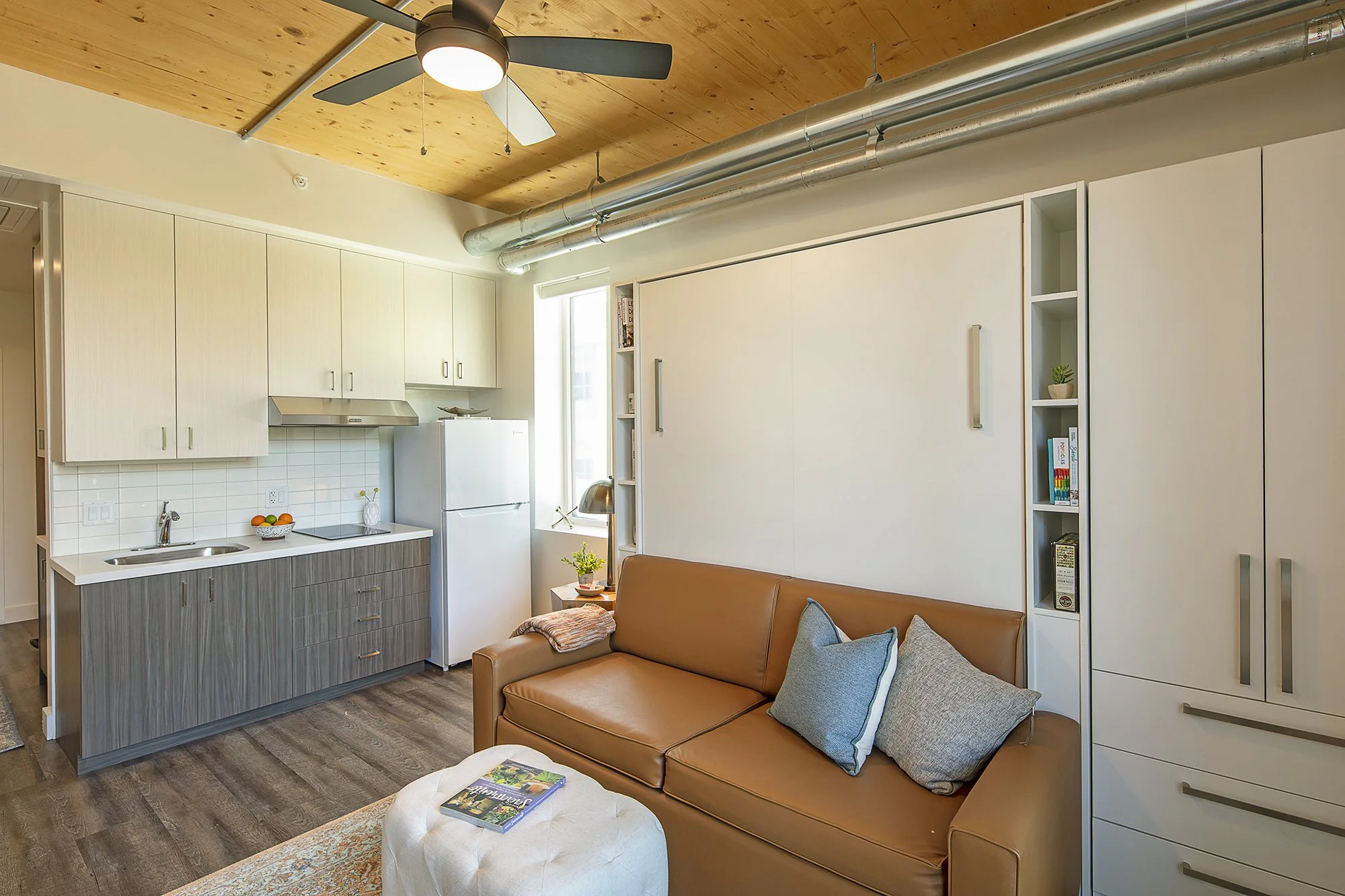 Staged studio living area with closed queen murphy bed/loveseat combo.