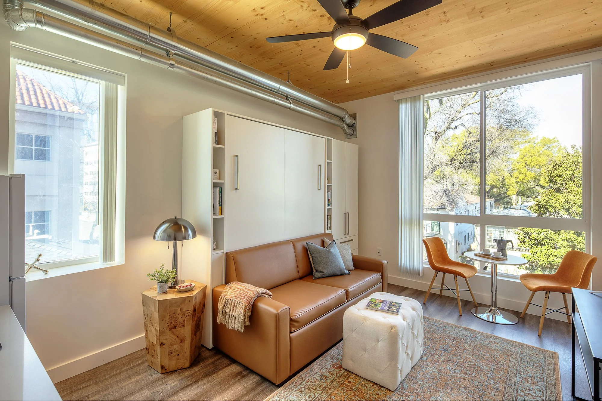 Staged studio living area with closed murphy bed/loveseat combo.
