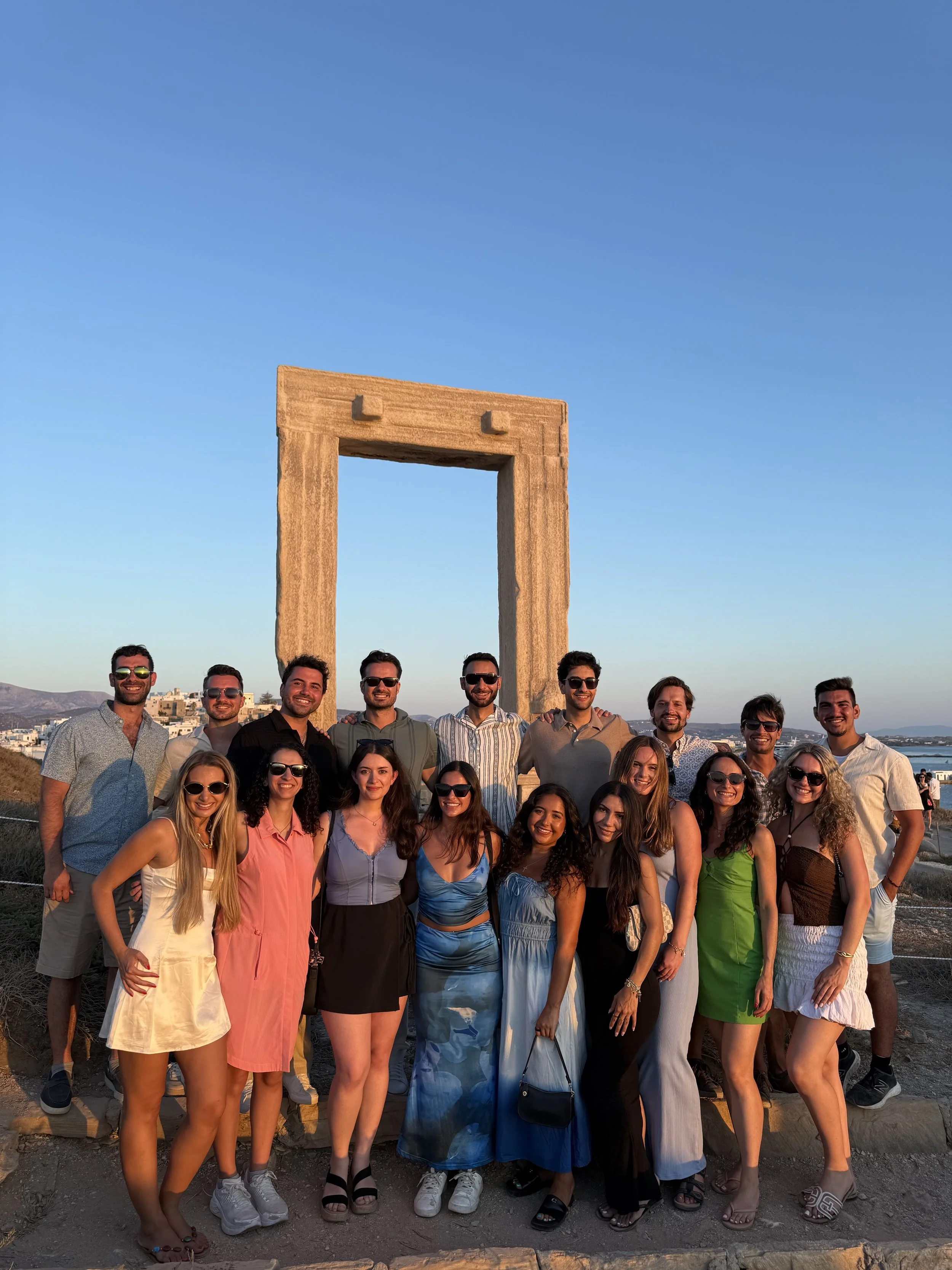 Group of people posing at the ancient Gate of Hercules in Greece during sunset