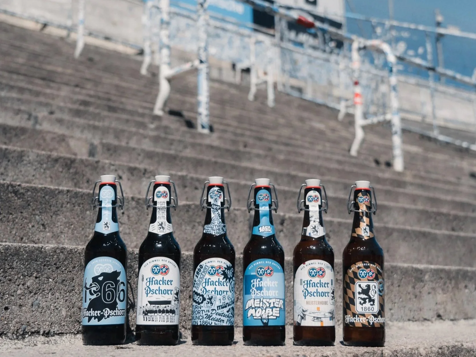 Six Hacker-Pschorr beer bottles lined up on concrete stadium steps