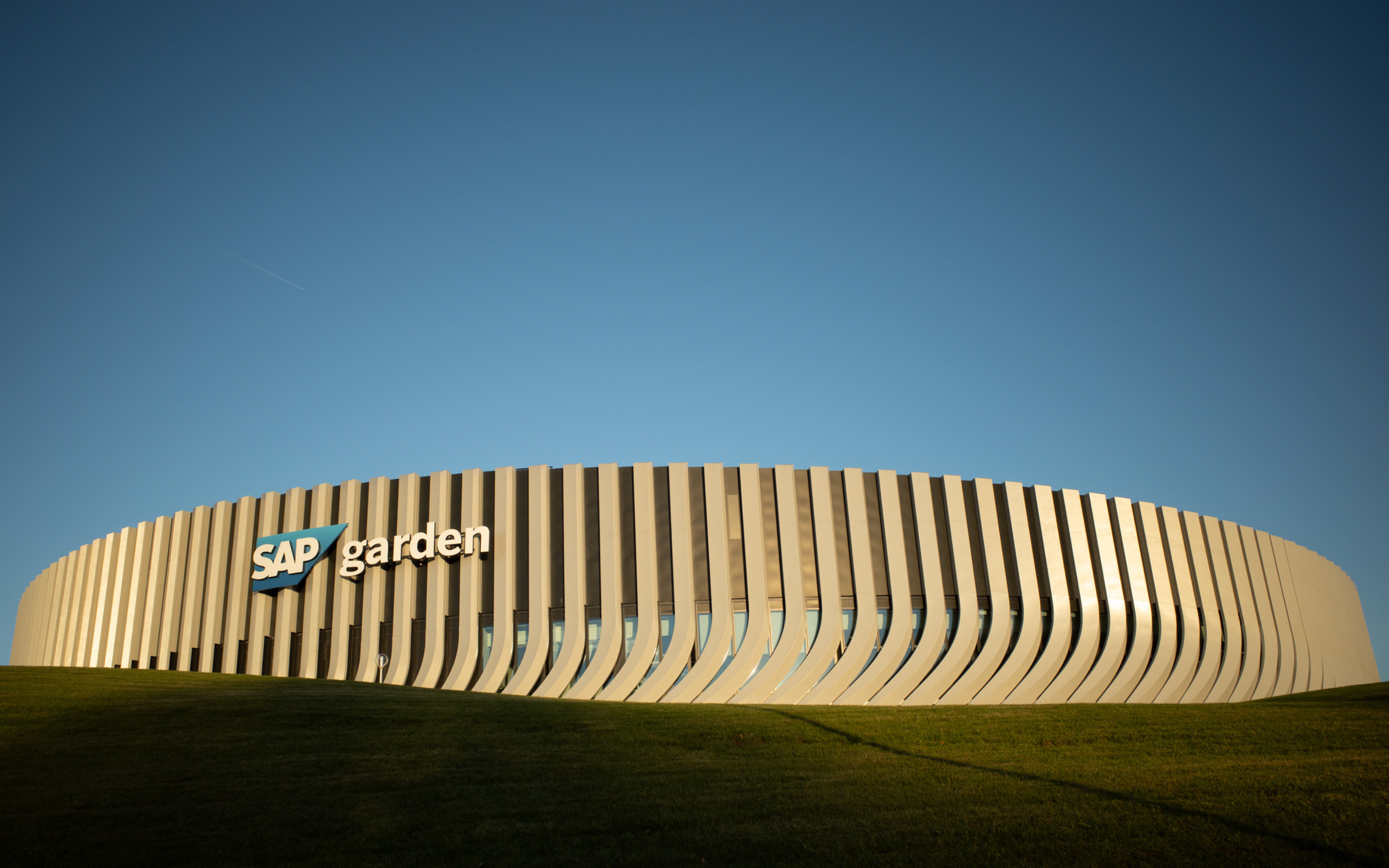 Exterior of the SAP Garden arena in Munich against a clear blue sky