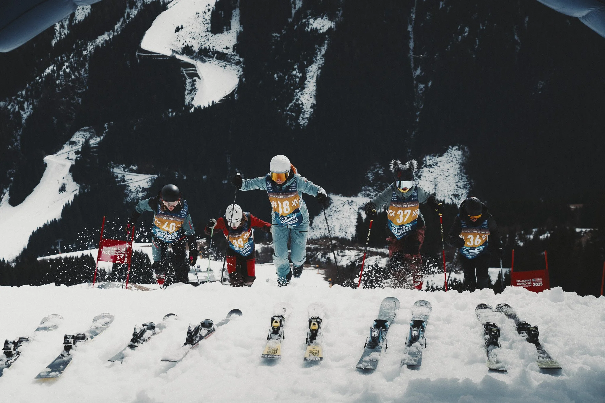 Five ski cross athletes in the start gate at the top of a snow-covered course at the chasing slopes festival in Saalbach. 