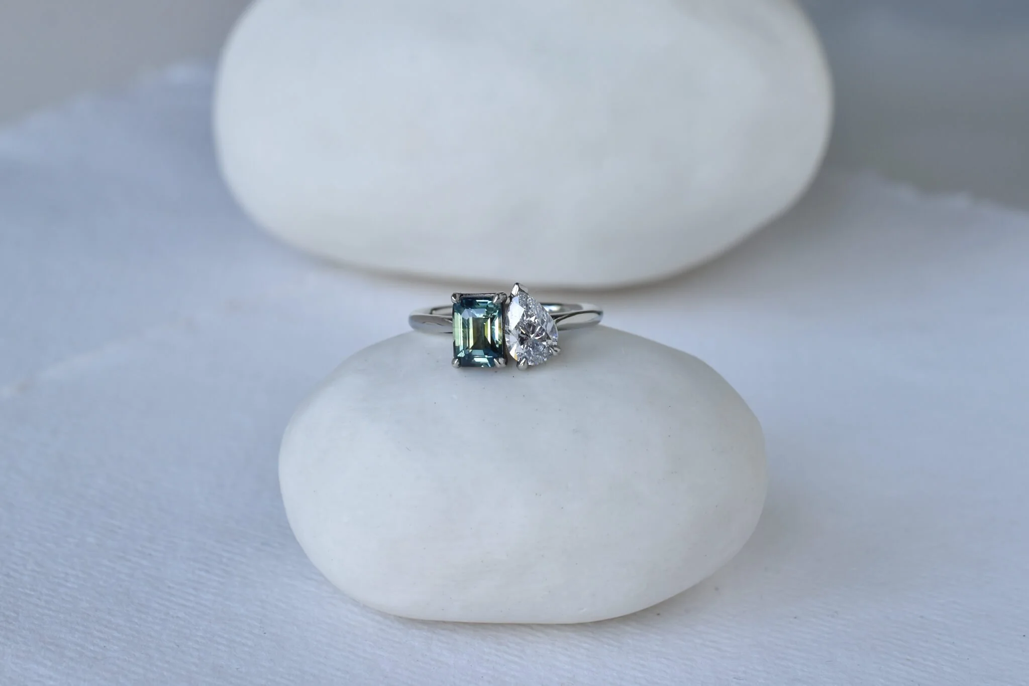 Blue green sapphire and diamond platinum ring on pebble