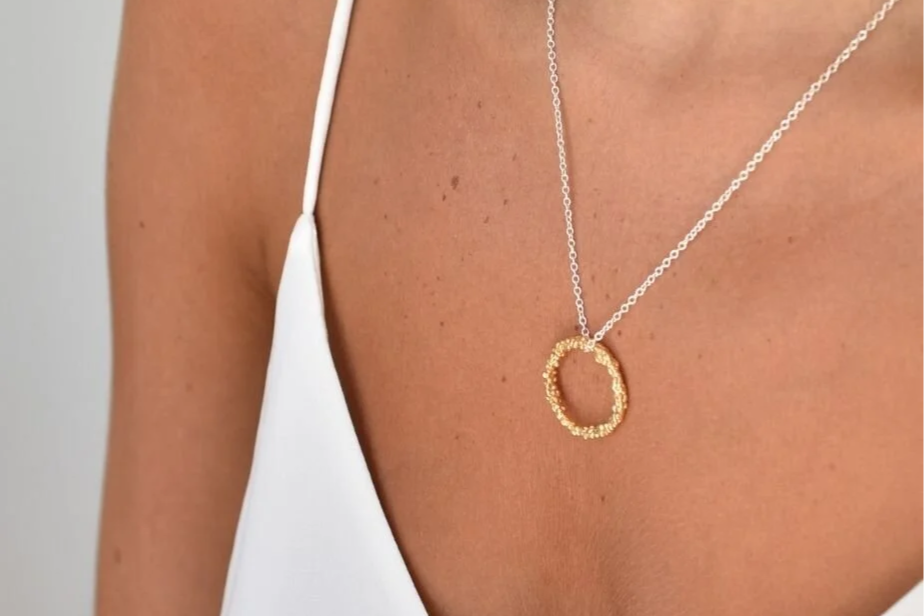 Gold circle pendant on silver chain on model's neck