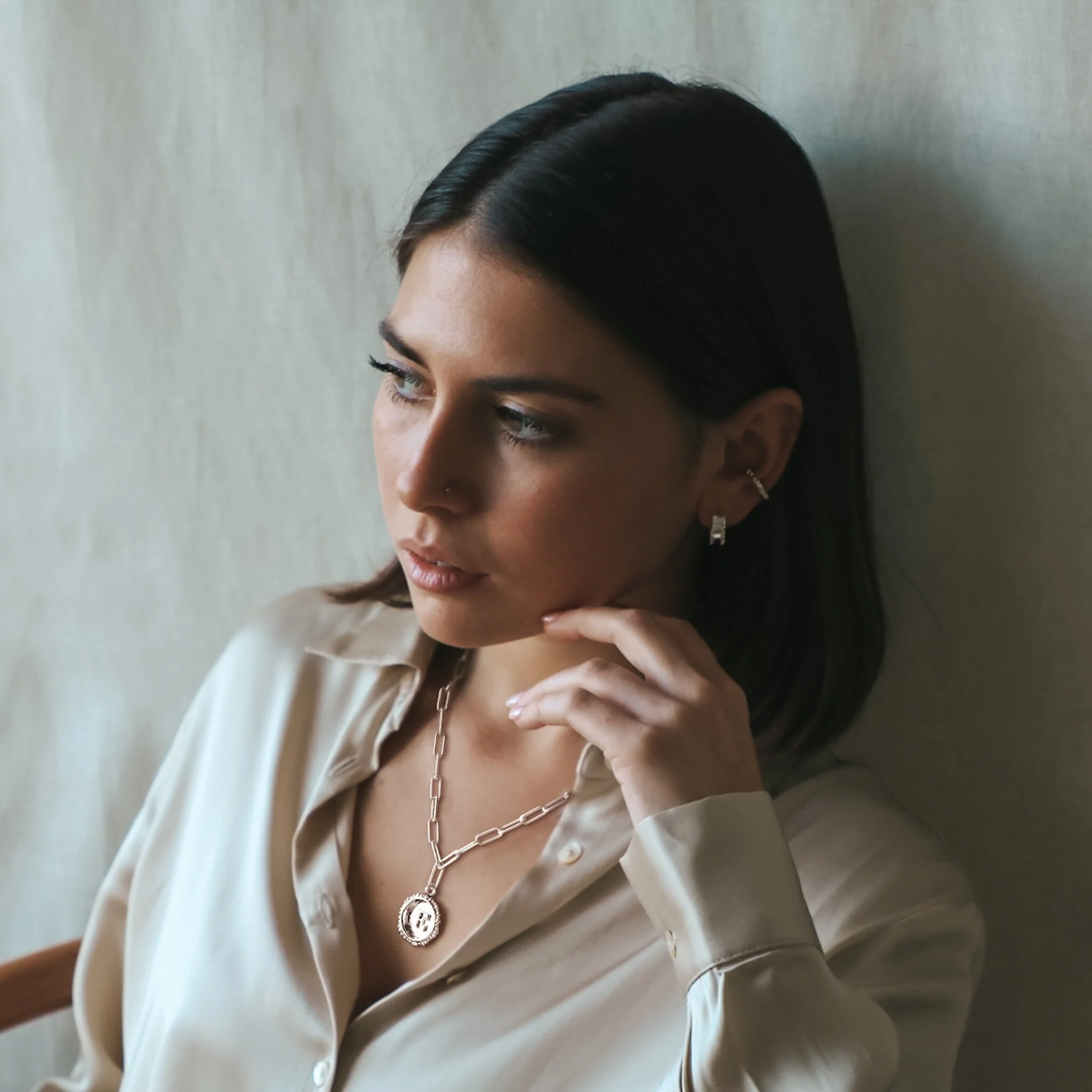 Sterling silver initial capital letter pendant necklace with rectangular chain shown on model with brown short hair. Made by Militza Ortiz