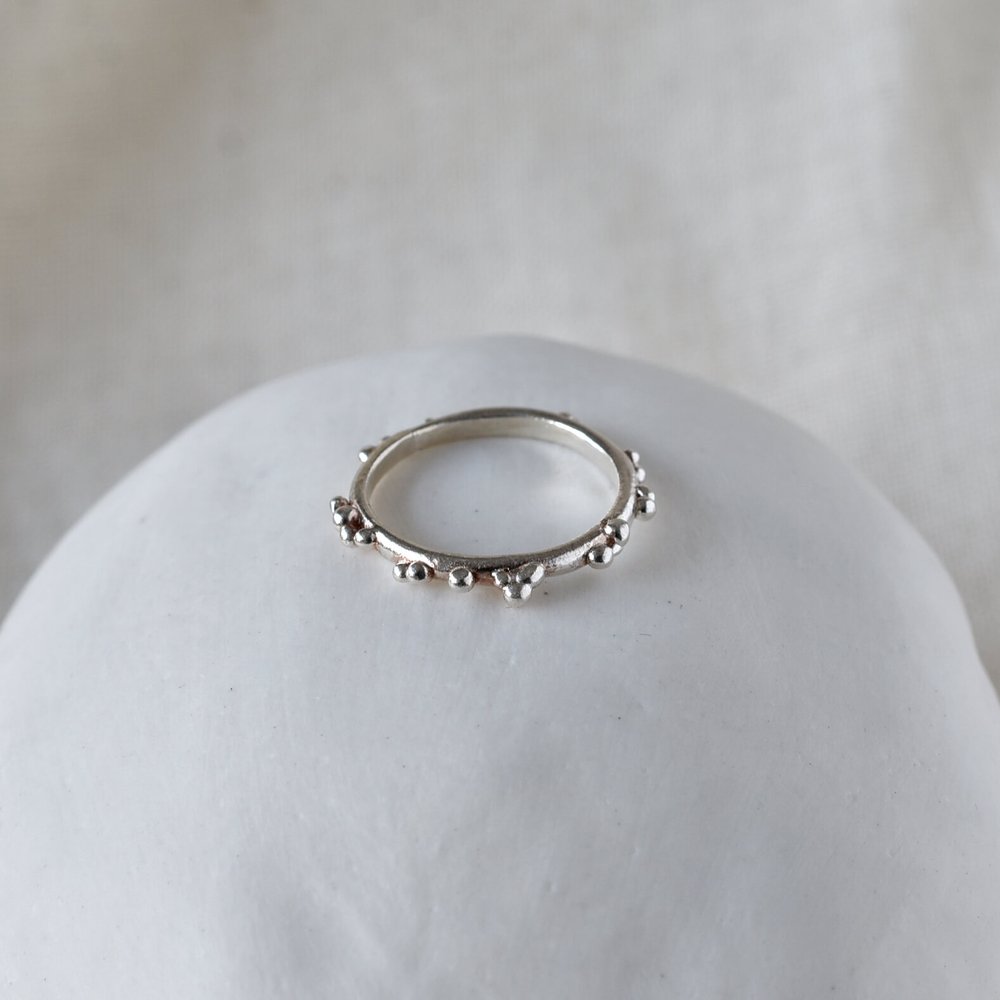 Skinny thin silver ring with dot bubble texture on pink background on ceramic stone- Militza Ortiz Jewellery